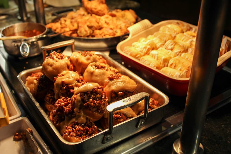 a platter with Sticky buns and other items in trays behind it 