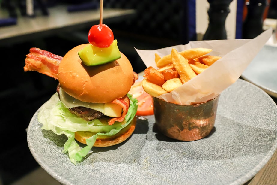 the cheeseburger is topped with a pickle and tiny tomato