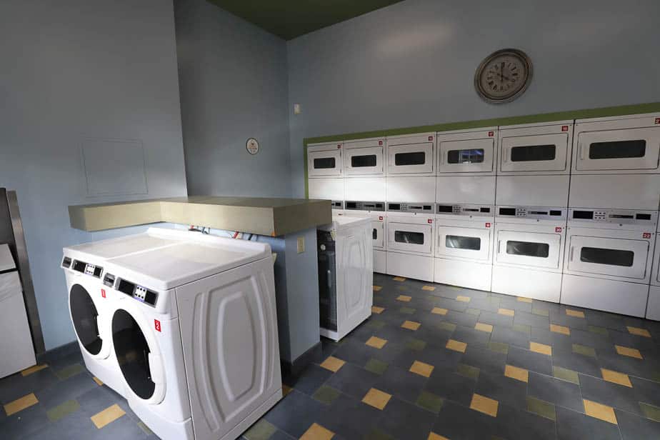 rows of washers sitting on the ground and dryers behind it 