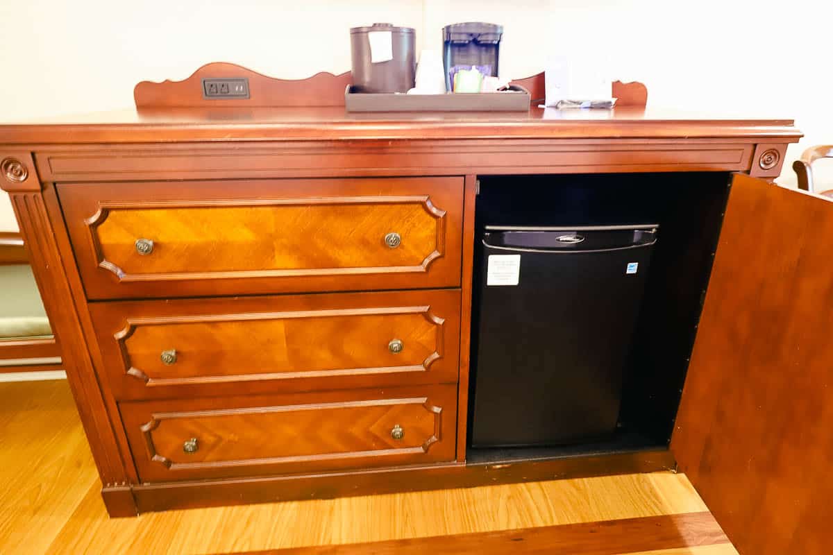 a dresser with three drawers and a cabinet that opens to reveal a mini fridge 