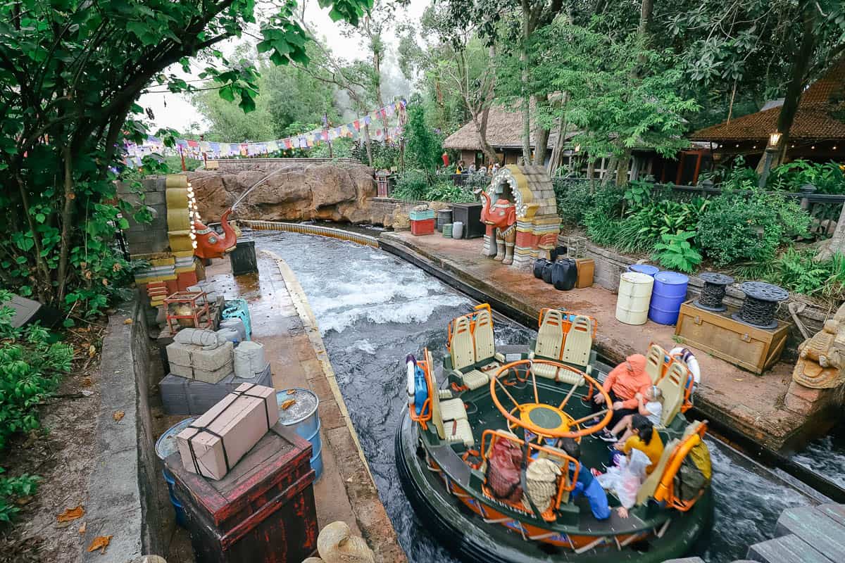 Kali River Rapids raft with guests riding in the center as statues of elephants spray water on them. 