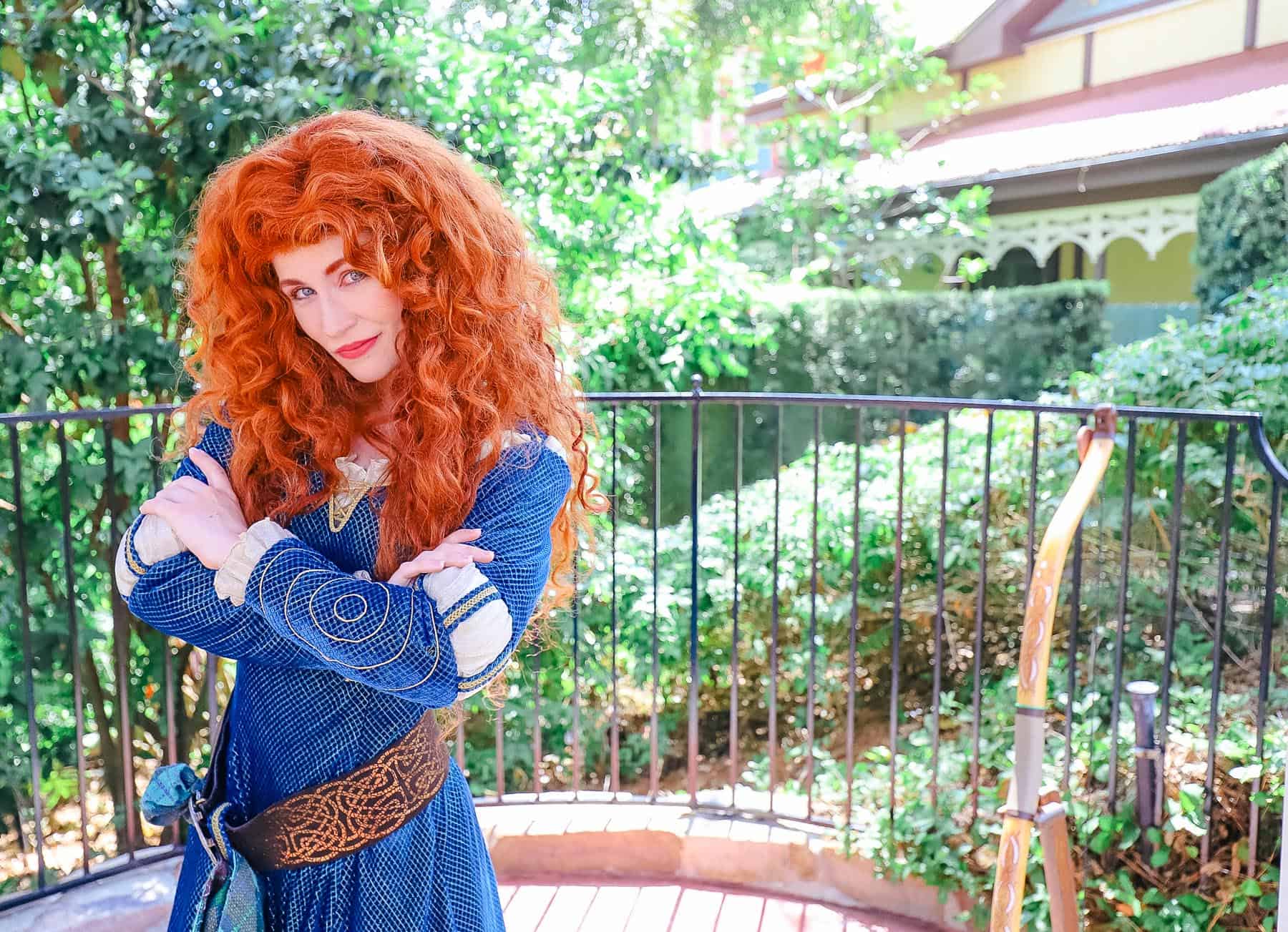 Merida poses at Magic Kingdom with her arms crossed.