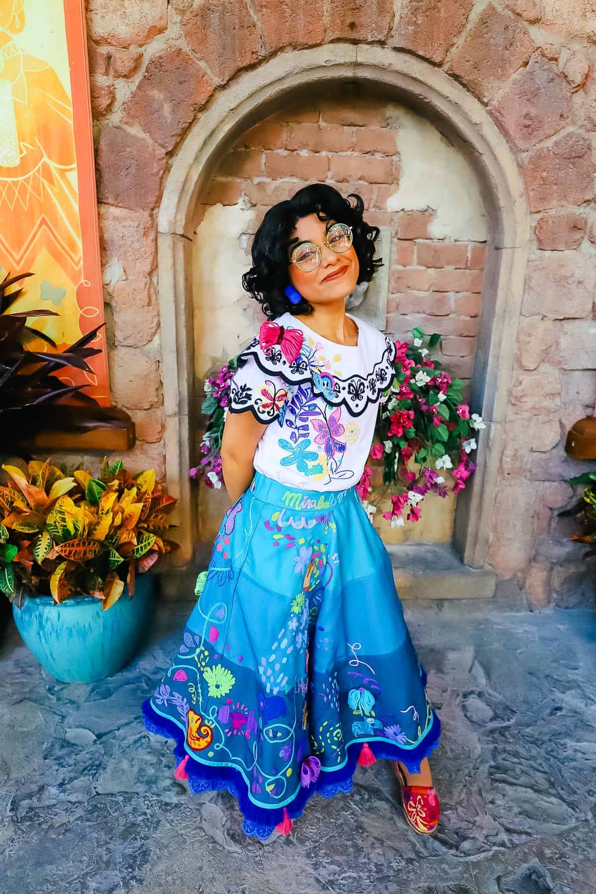 Mirabel posing for photos. Her name is stitched in virbrant colors across the waistband of her skirt.
