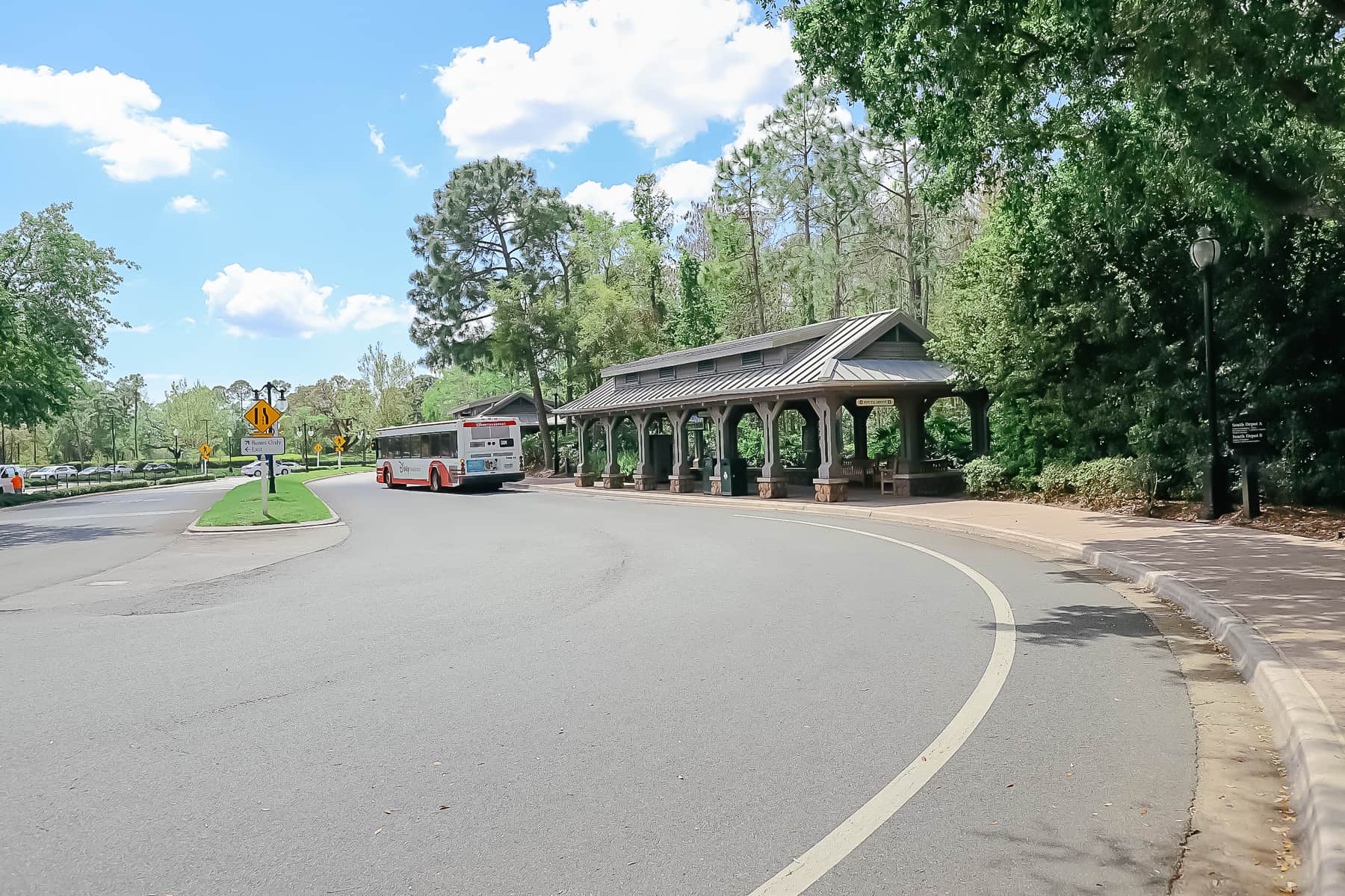 a bus pulling away from the bus stop at the front entrance of Port Orleans Riverside 