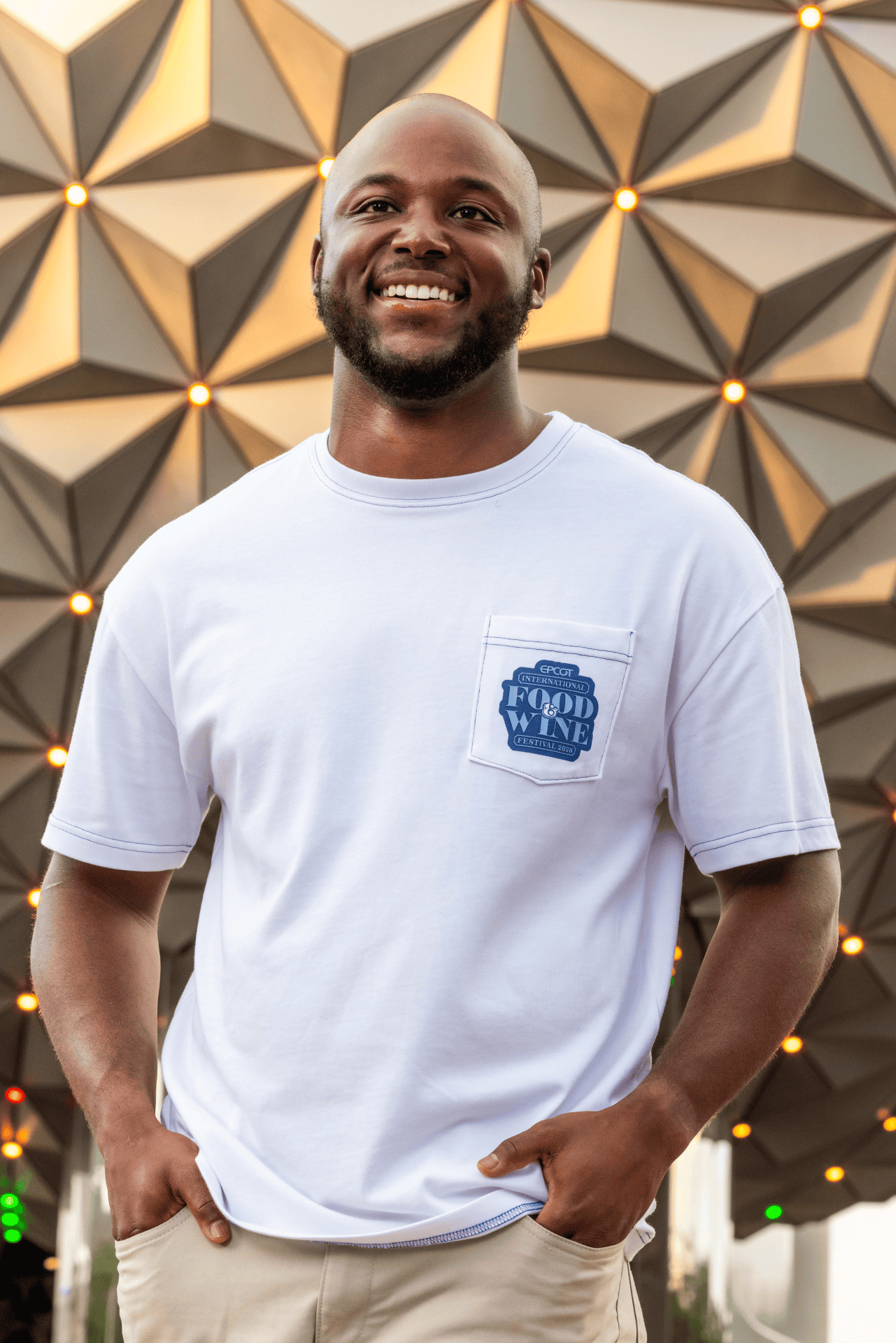 a man wearing a Food and Wine logo pocket tee in front of Spaceship Earth