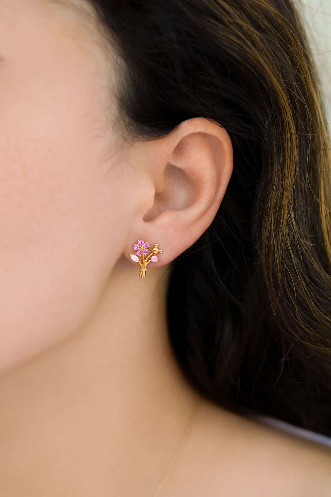 a model wearing a pink Mickey floral earring 