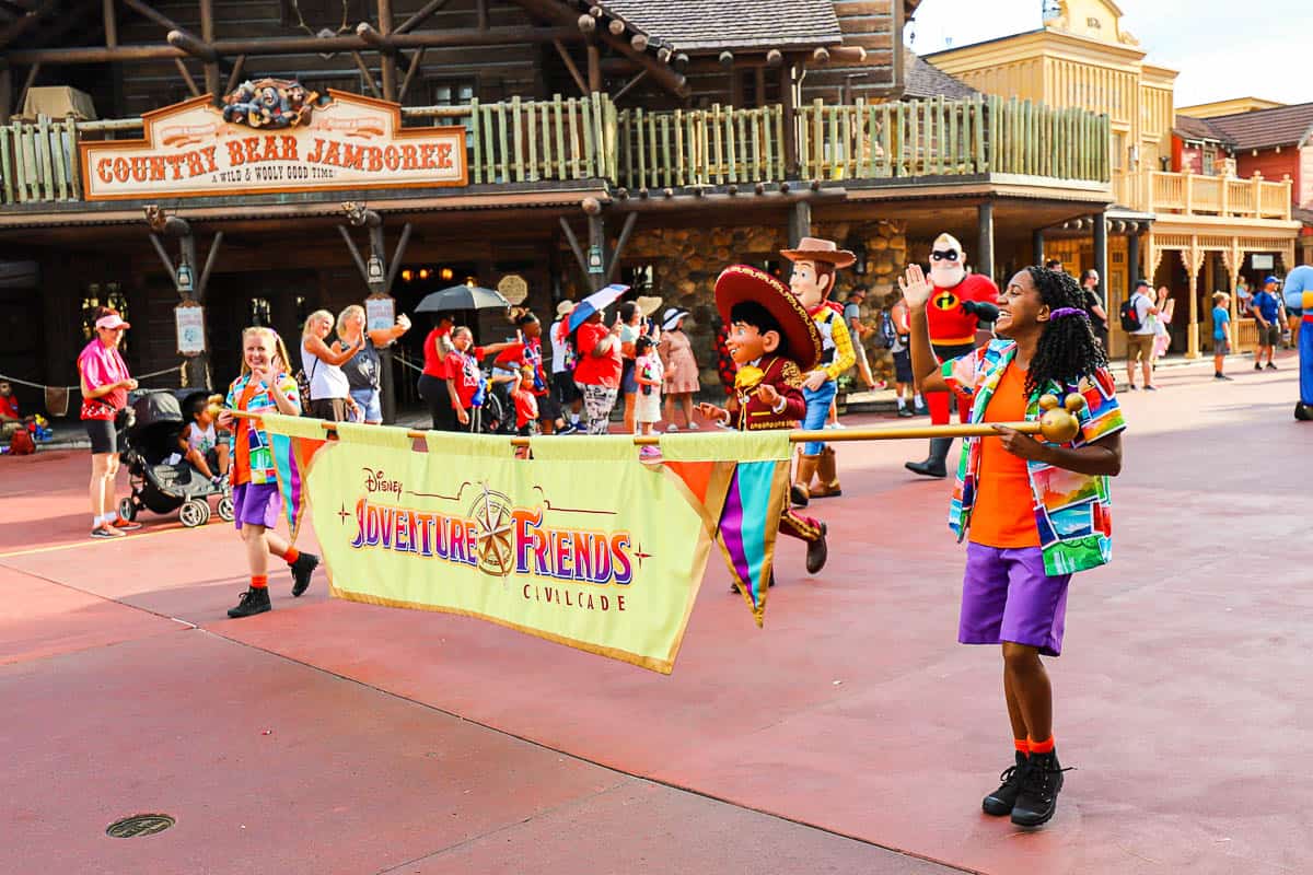The cast members carrying the banner at the start of the Adventure Friends Cavalcade in Frontierland. 