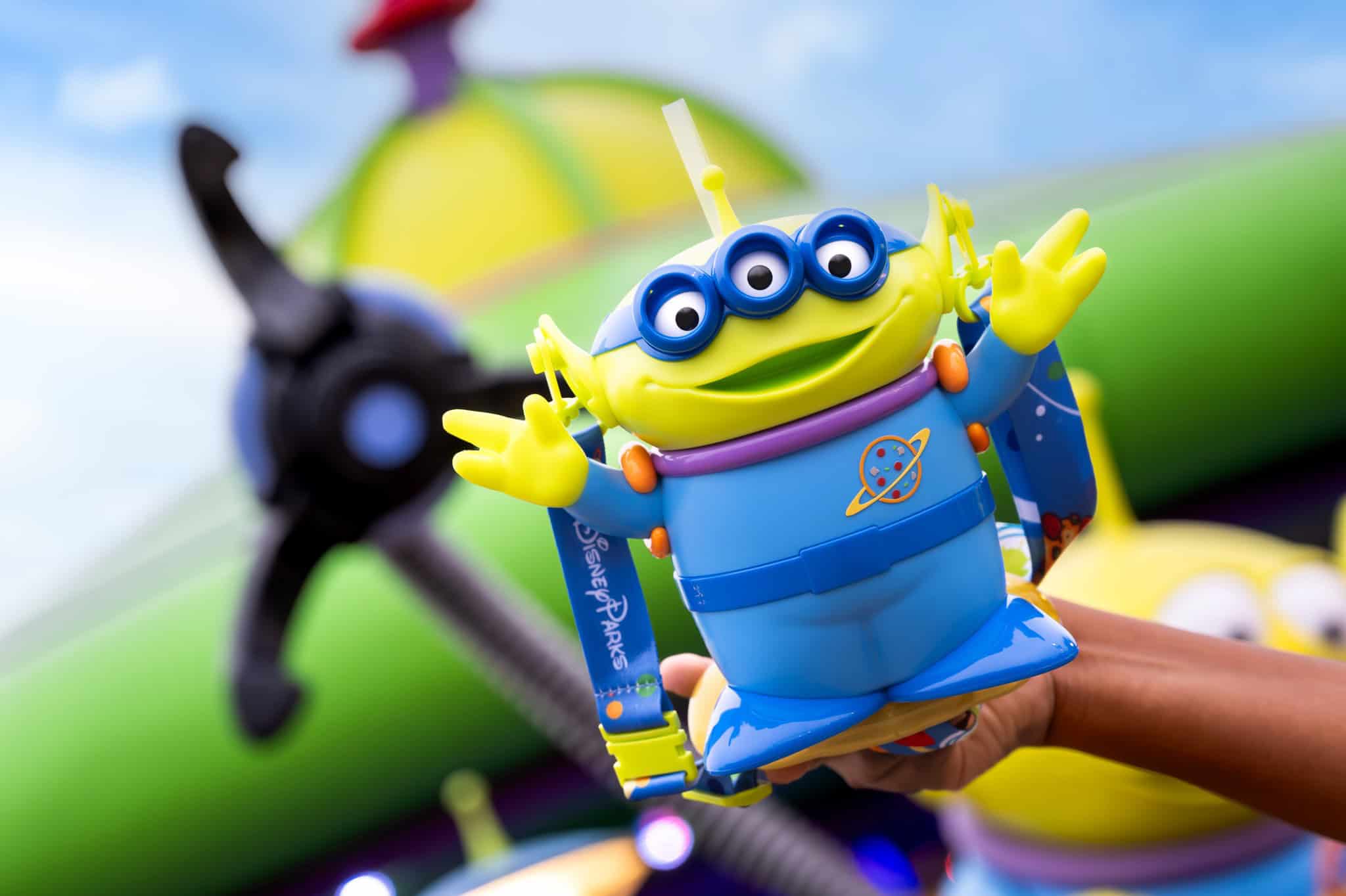 a hand holding a little green alien sipper cup 