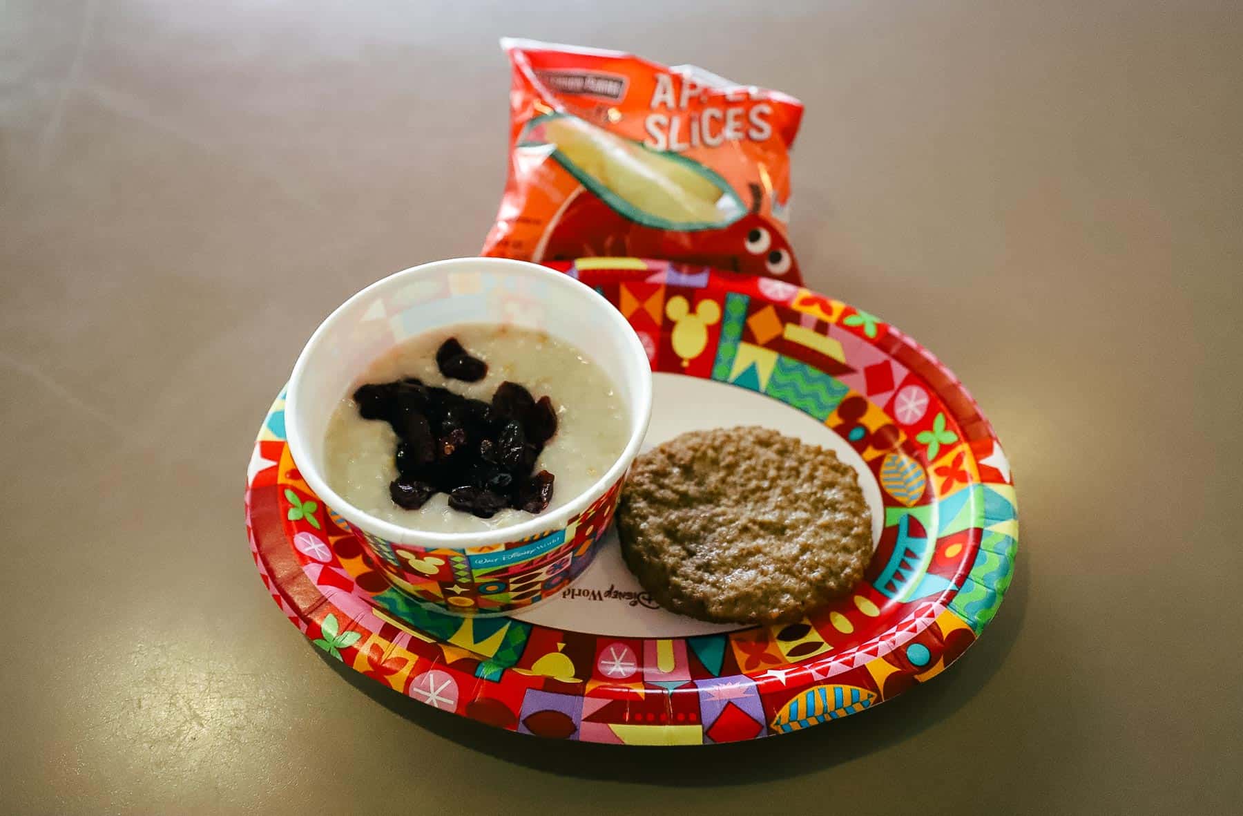 a kids' meal platter with oatmeal and dried cranberries, turkey sausage and a small pack of apple slices 