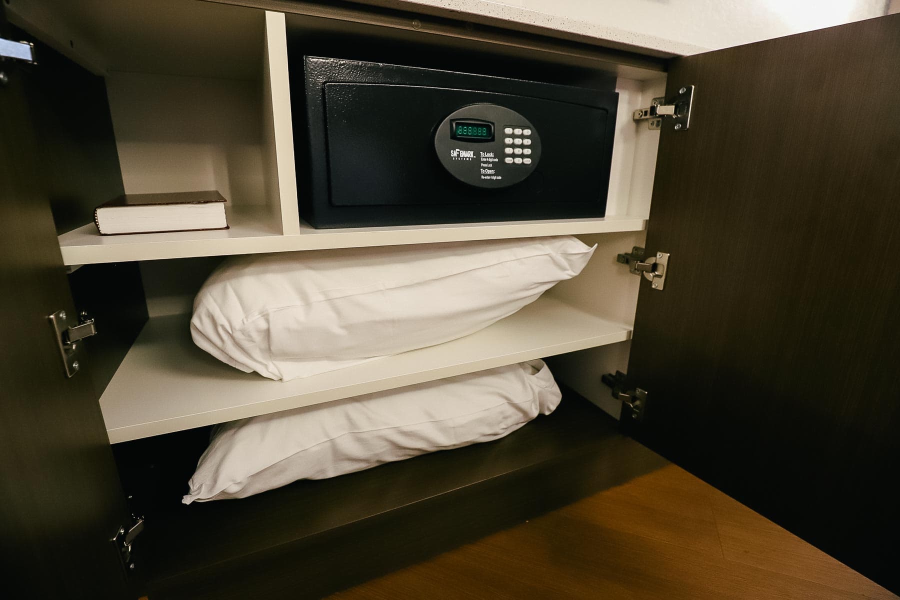 The cabinet opens to reveal an in-room safe and extra pillows for the Murphy Bed. 