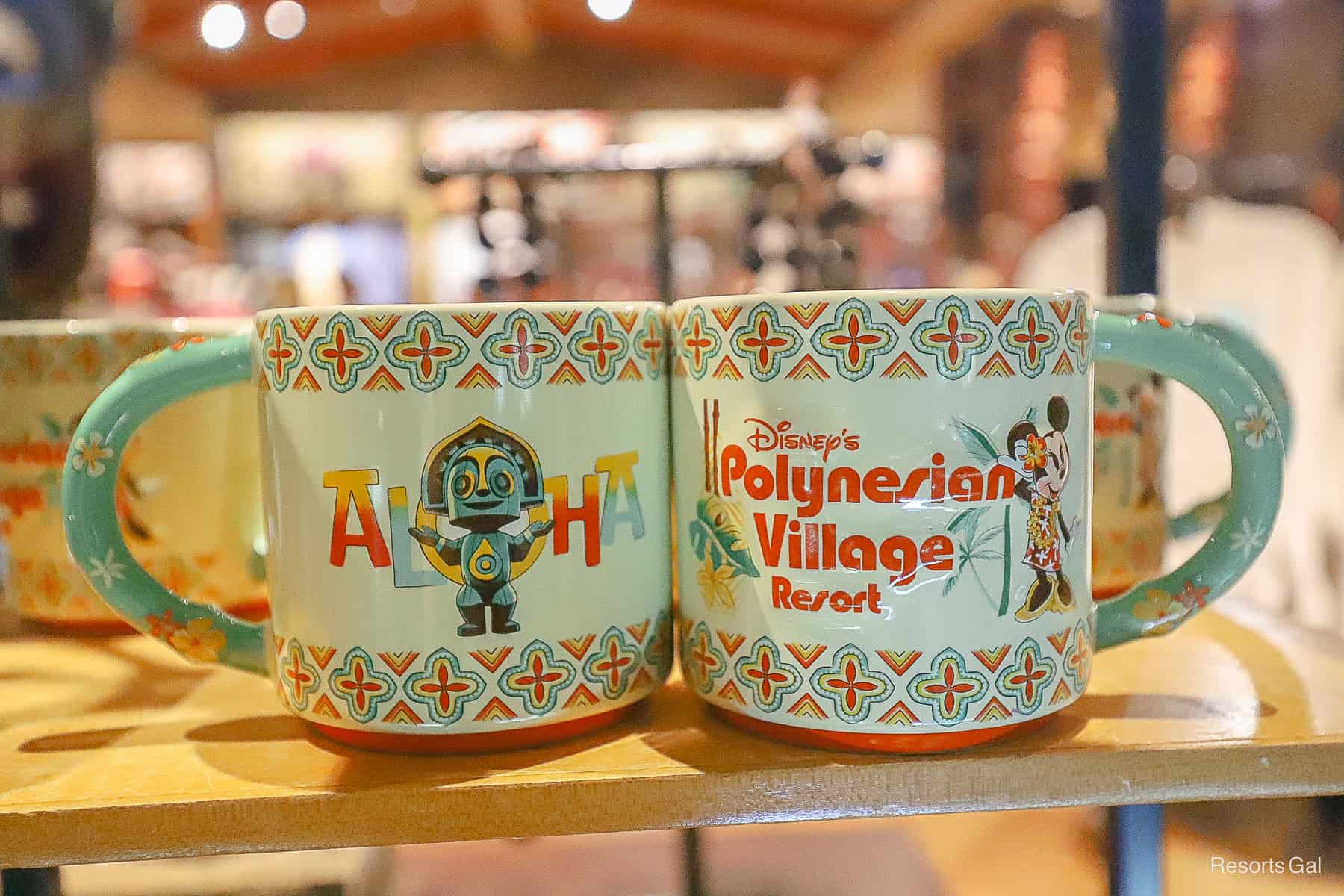 Aloha mugs front and back side at in mint green with orange accents, Minnie Mouse, and a Tiki Statue 