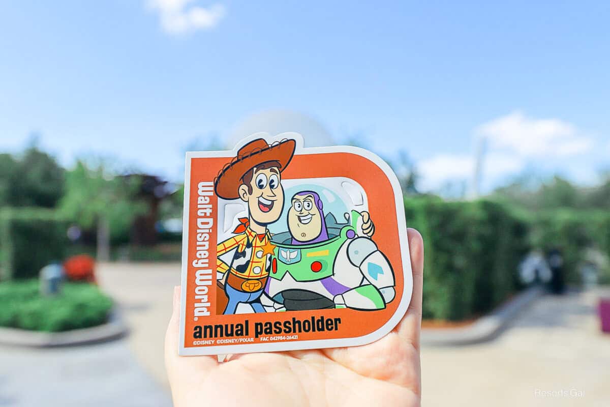 a hand holding an annual passholder magnet with Woody and Buzz