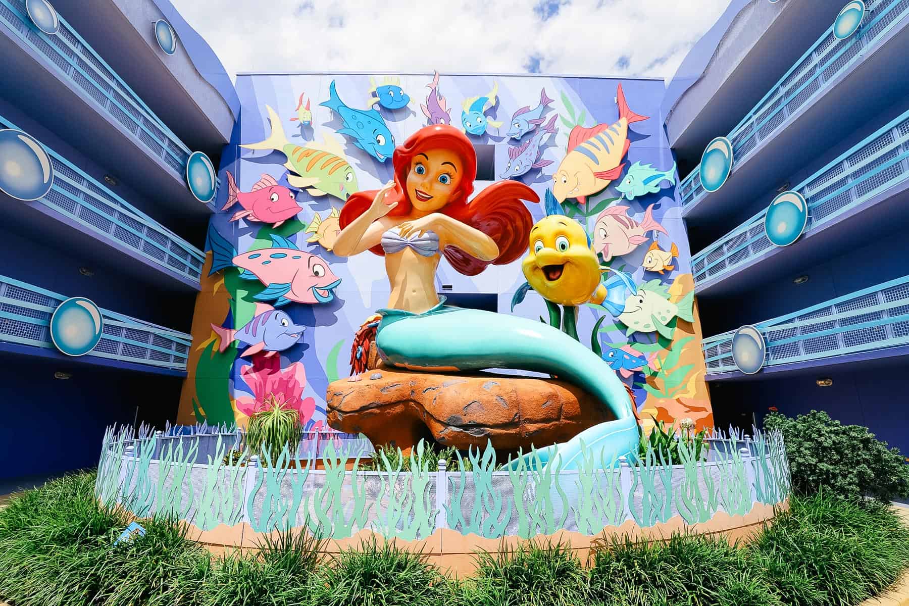 Ariels Little Mermaid statue with cutouts of fish surrounding her. 