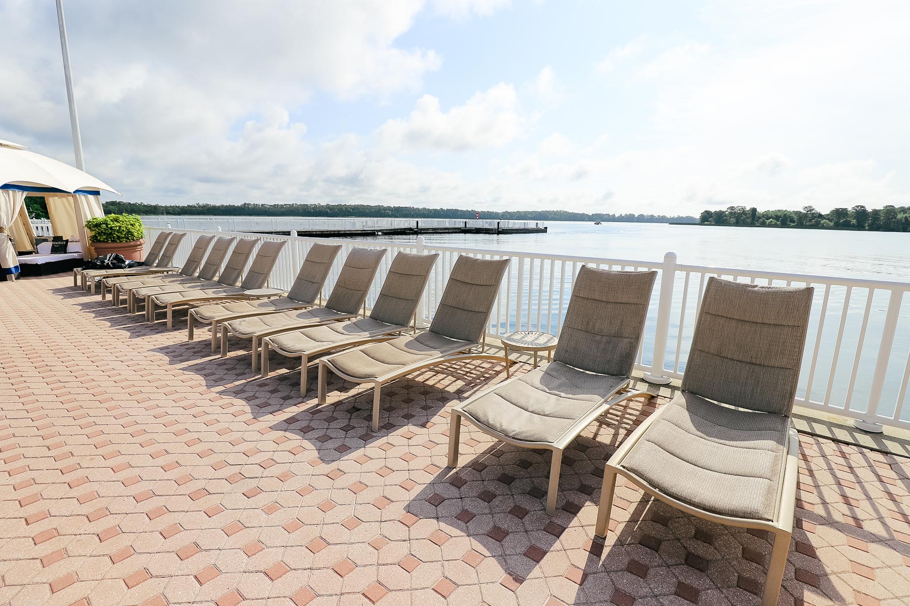 a row of lounge chairs sitting between the Contemporary Resort's pool and Bay Lake 