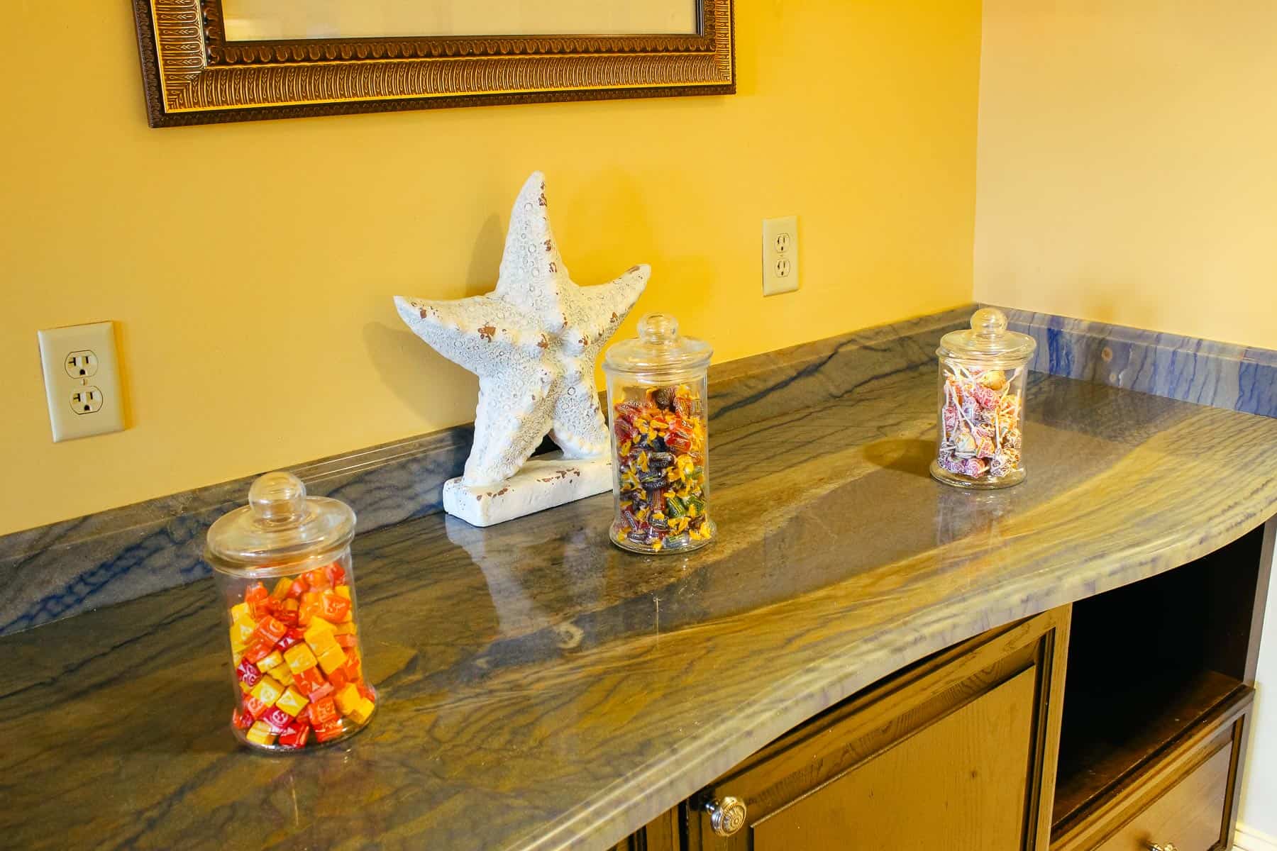 a counter with three jars of candy like Starbursts, Jolly Ranchers, and Dum Dums 