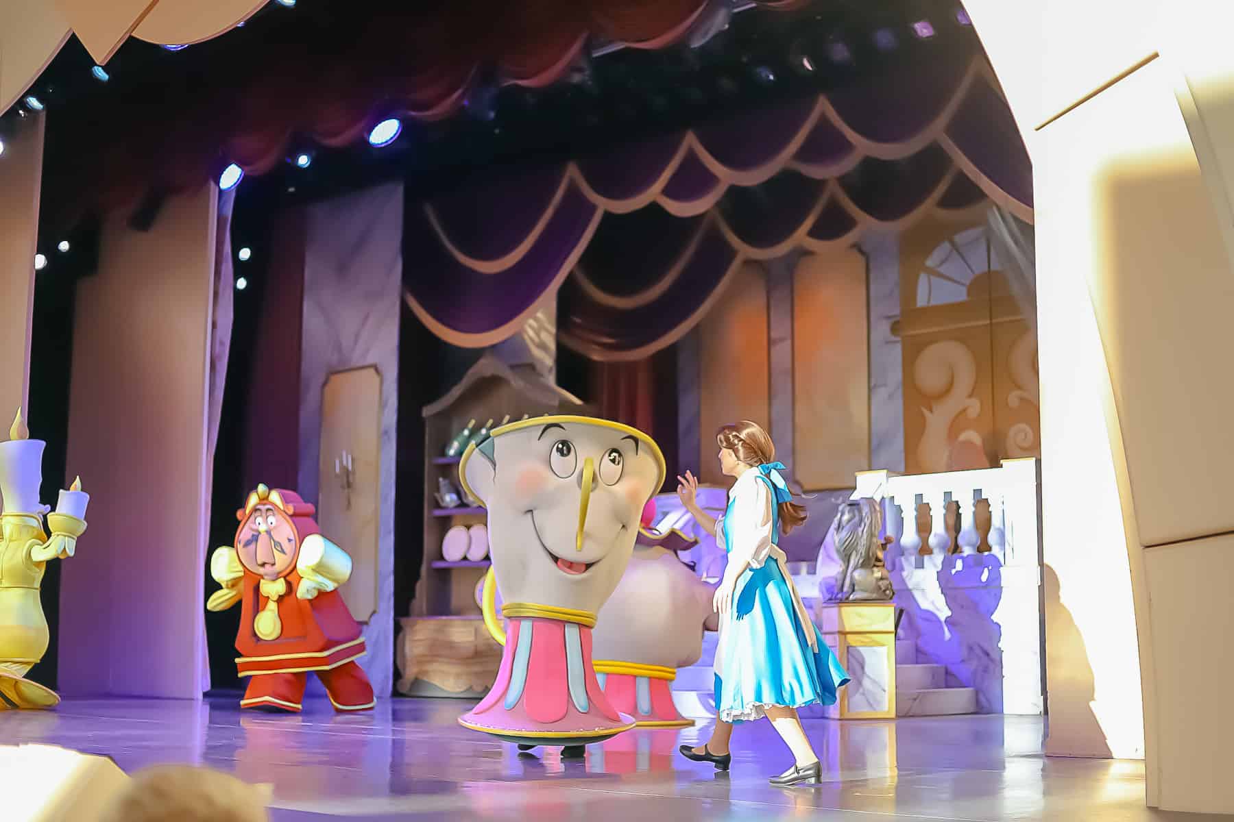 Belle singing with Chip on a theater stage at Disney's Hollywood Studios. 
