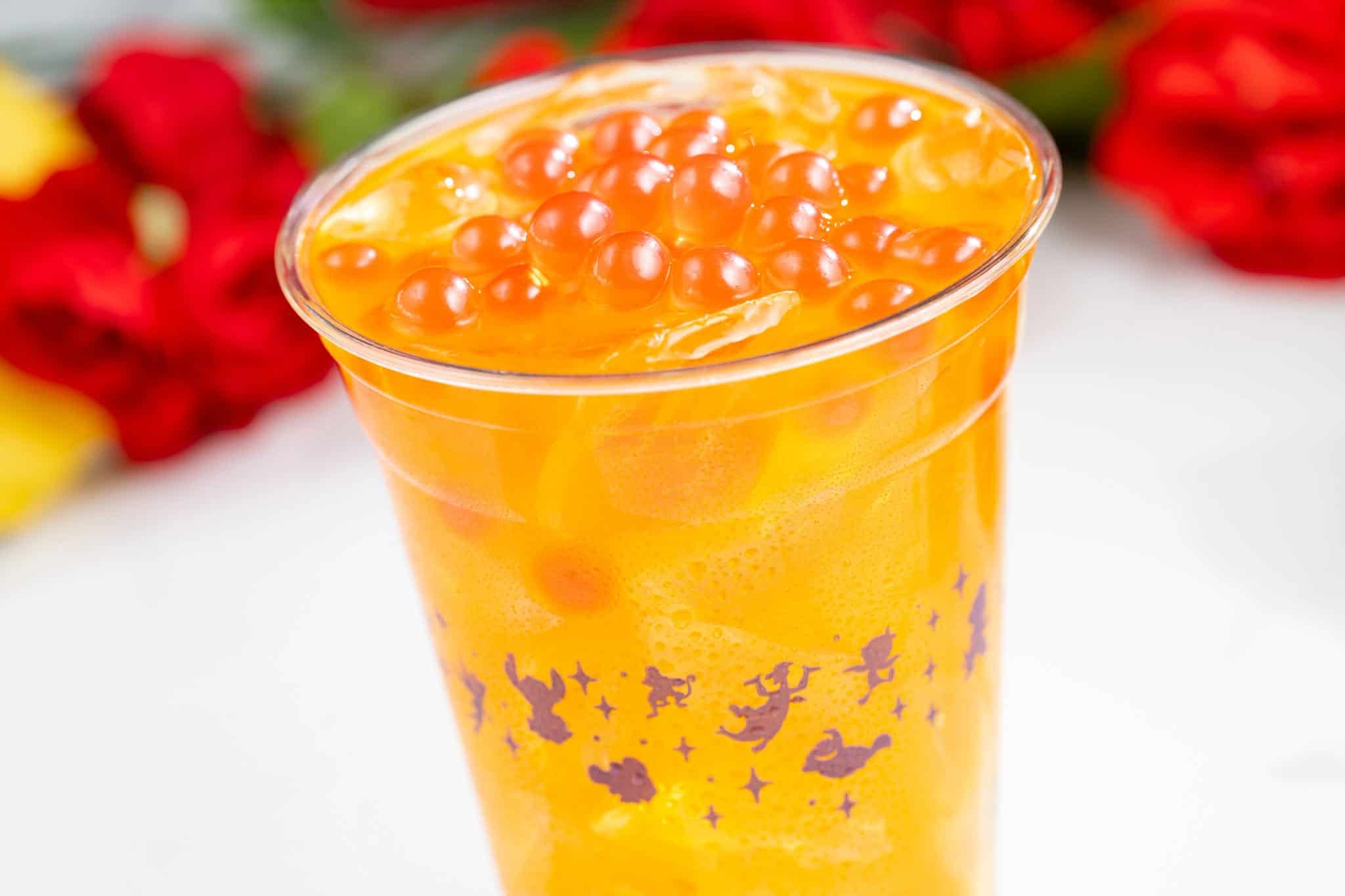 a cup of orange drink with boba pearls