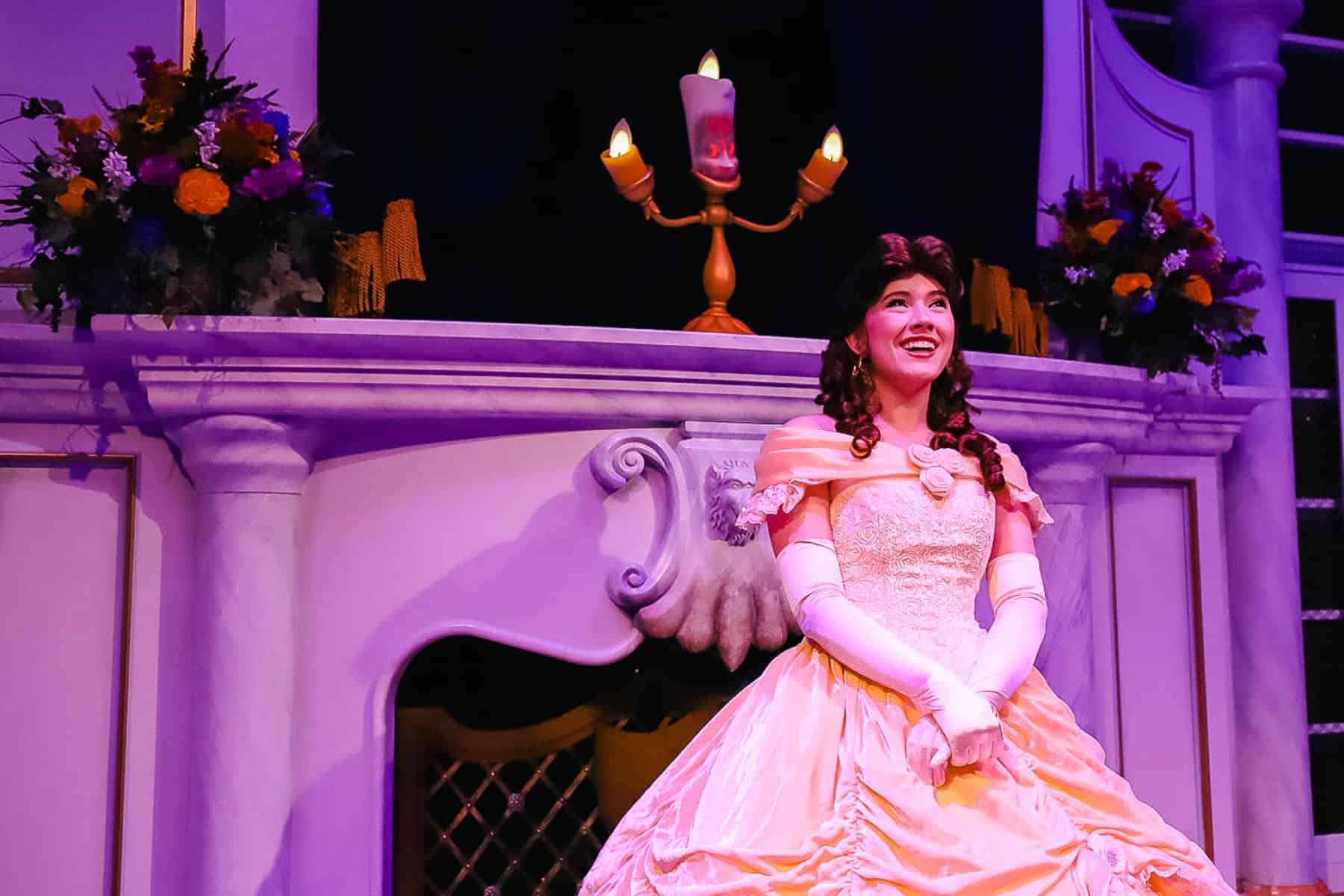 Belle smiles in front of Lumiere at Enchanted Tales. She is wearing her yellow dress. 