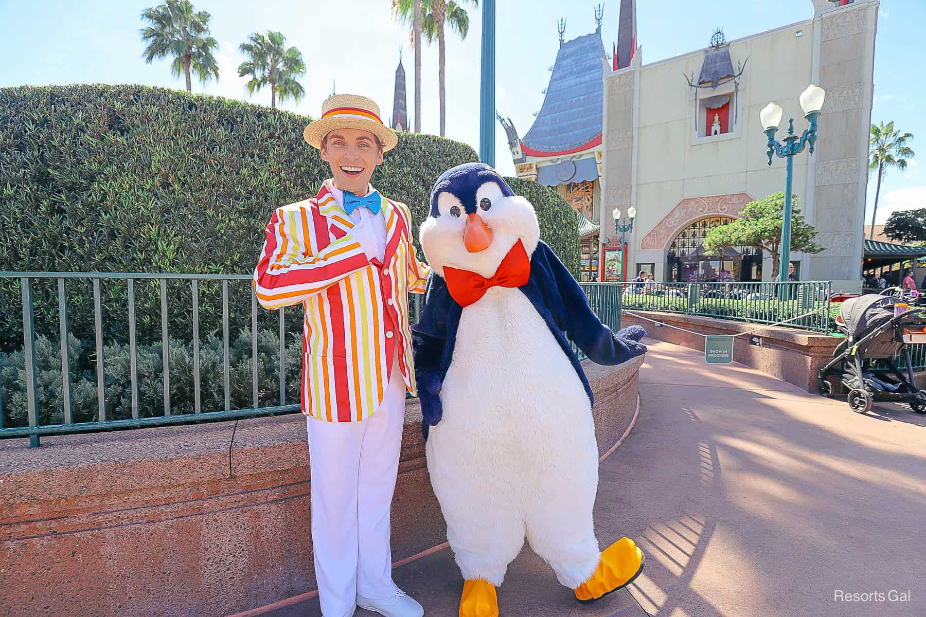Bert wears a striped jacket in red, yellow, and orange and Mr. Penguin wears a red bow 