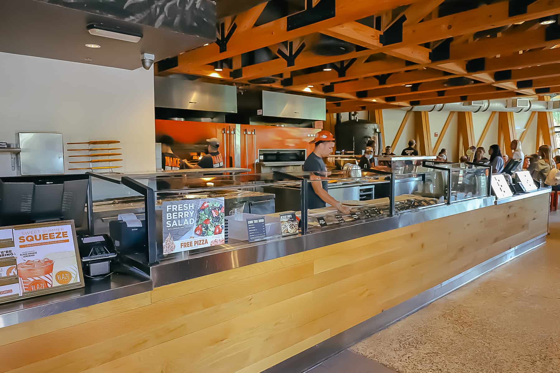 Shows a cast member preparing toppings to go on a pizza. 