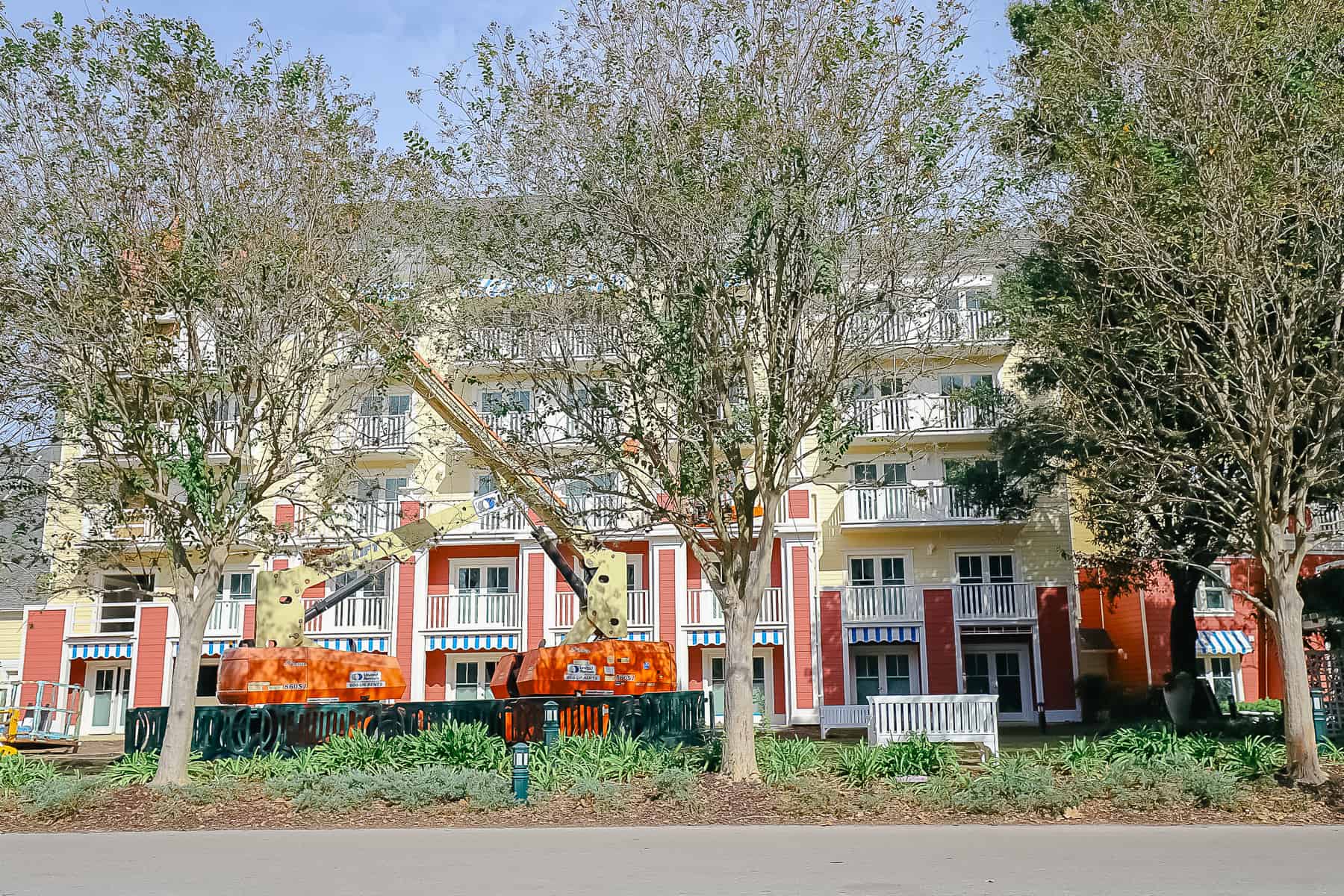 An updated photo of the same area that shows new red and yellow paint and blue and white awnings at Disney's Boardwalk Villas. 