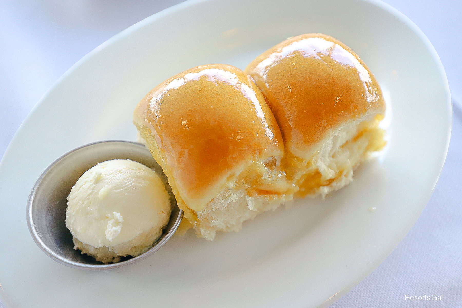 two rolls covered in honey with a side of soft butter 