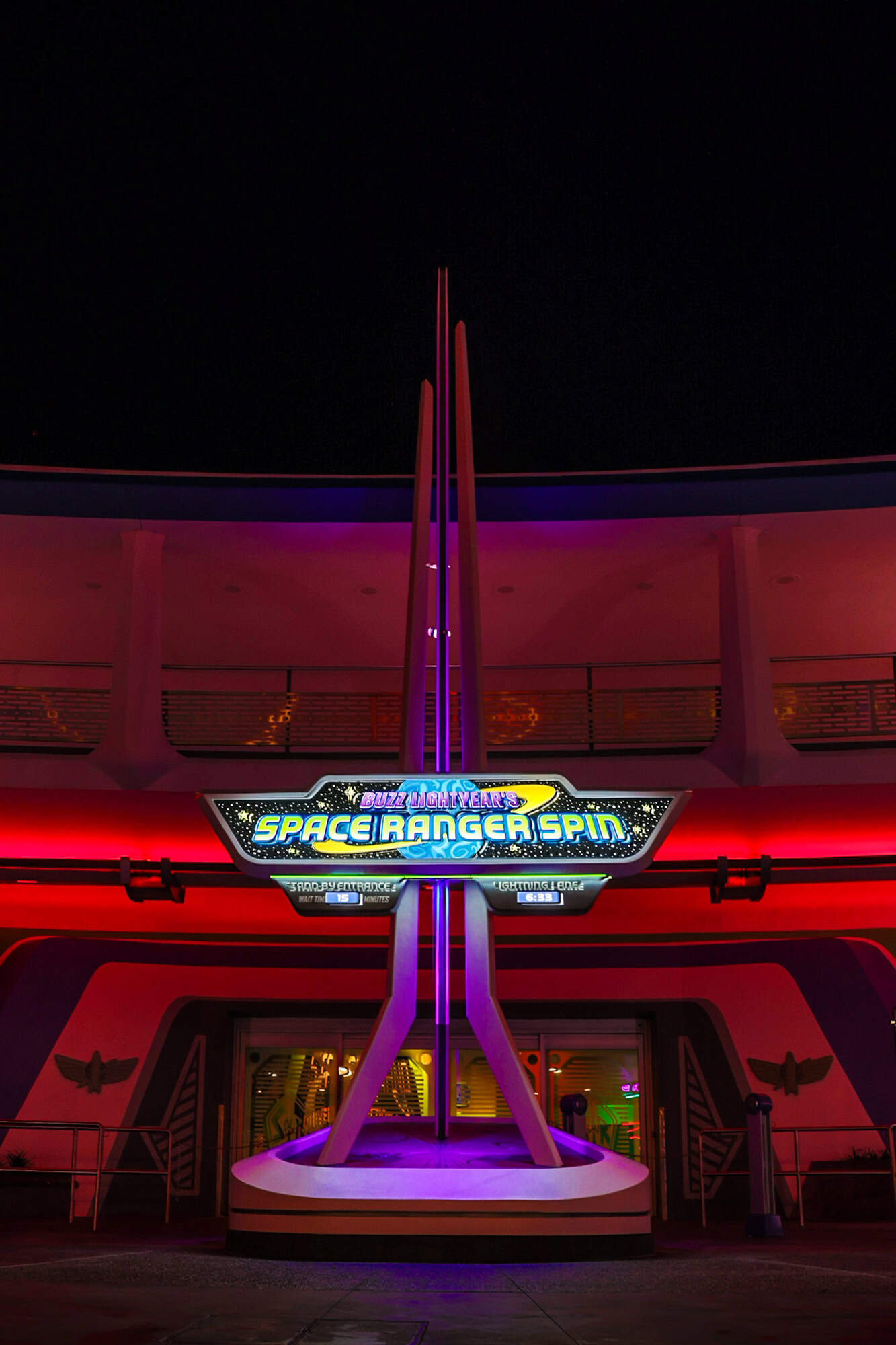 a vertical view that shows how the Buzz Lightyear Space Ranger Spin signage lights up at night 