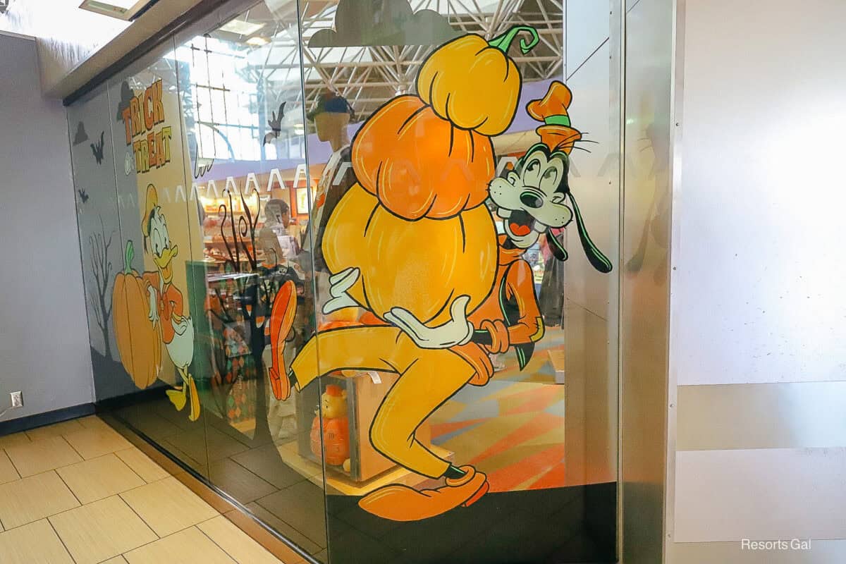Goofy carries a stack of pumpkins in the Contemporary's gift shop Halloween window display