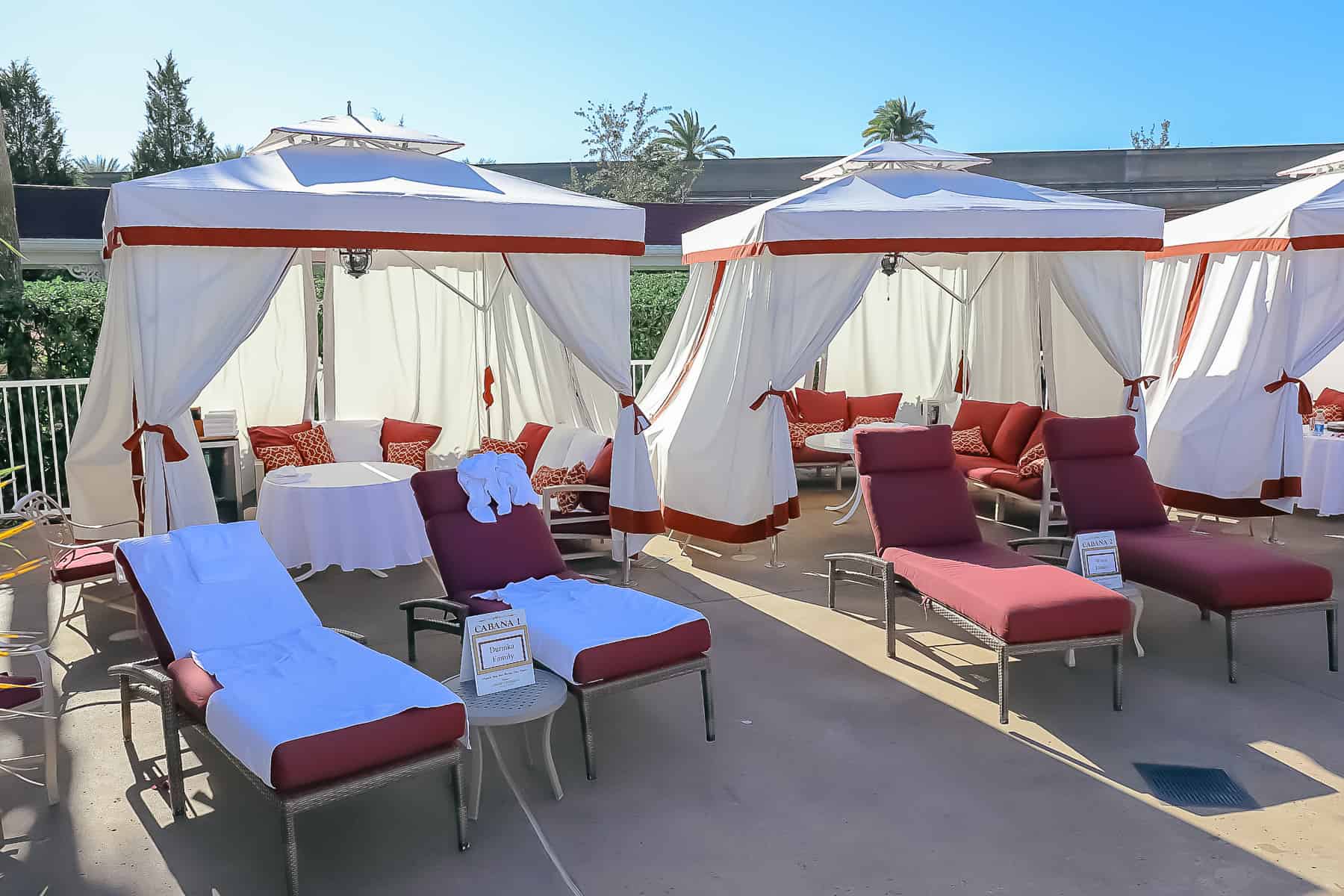 cabanas with red lounge chairs and white canopies 