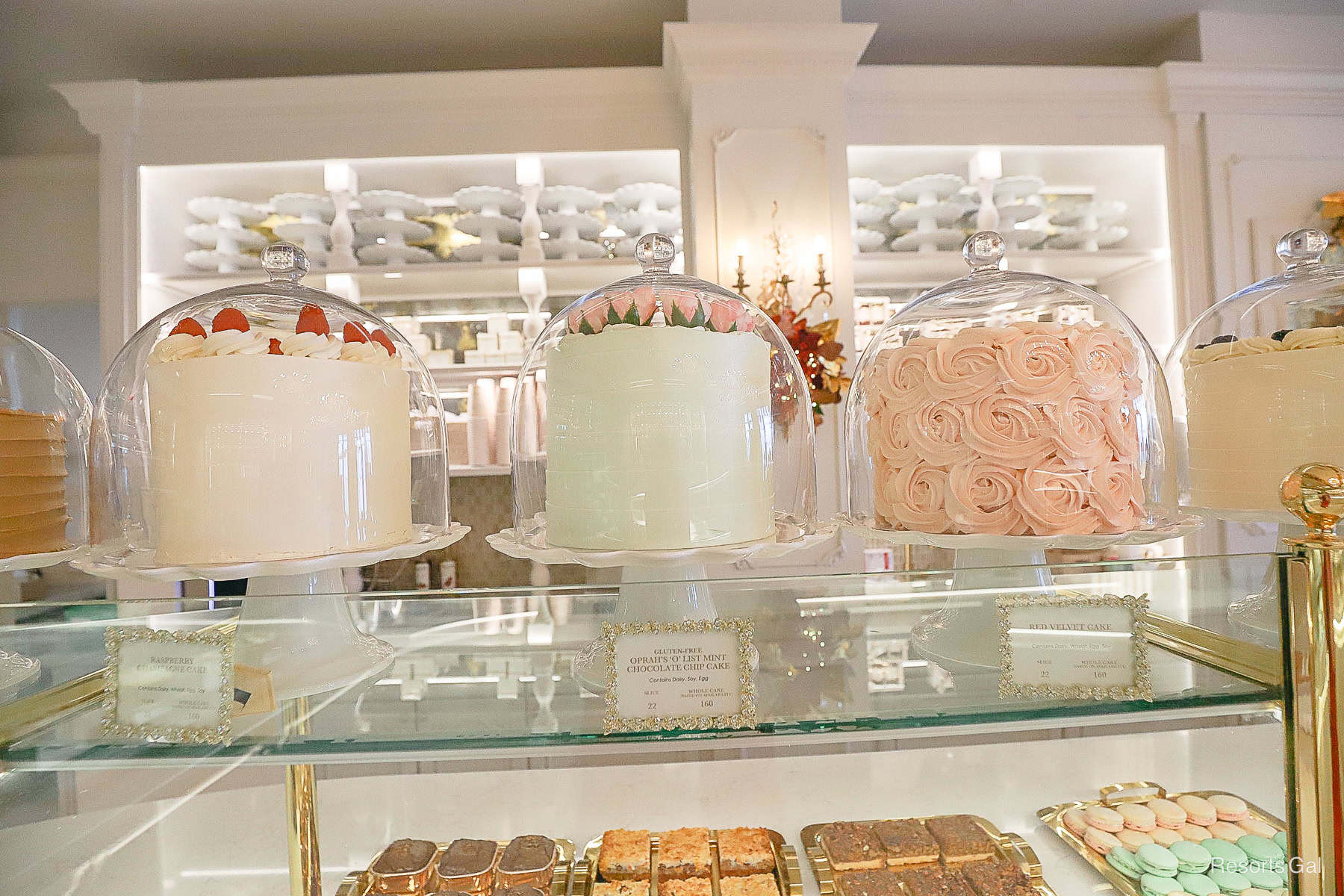 a display with a variety of cakes sitting on stands in white, mint green, and pink