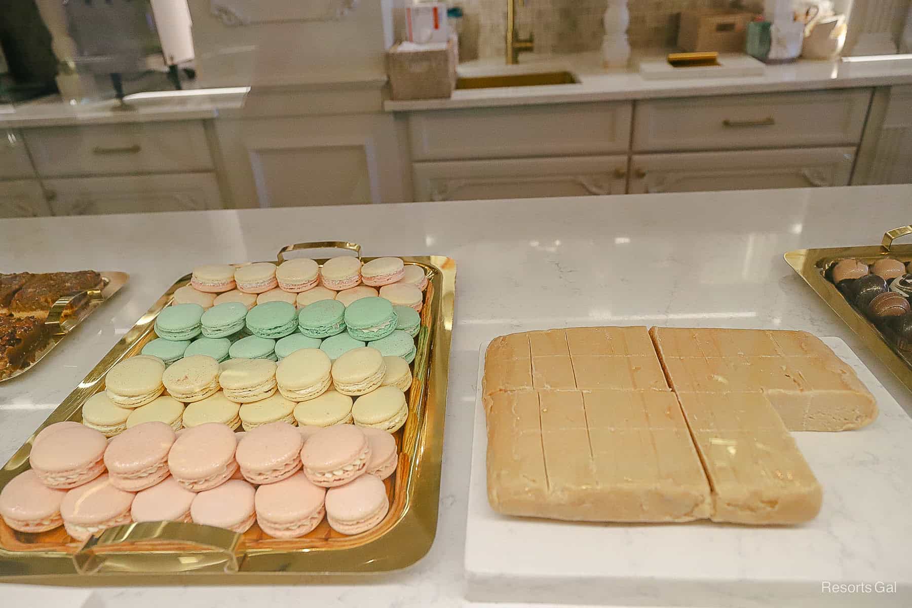 macarons in yellow, pink, and green next to a slab of fudge 