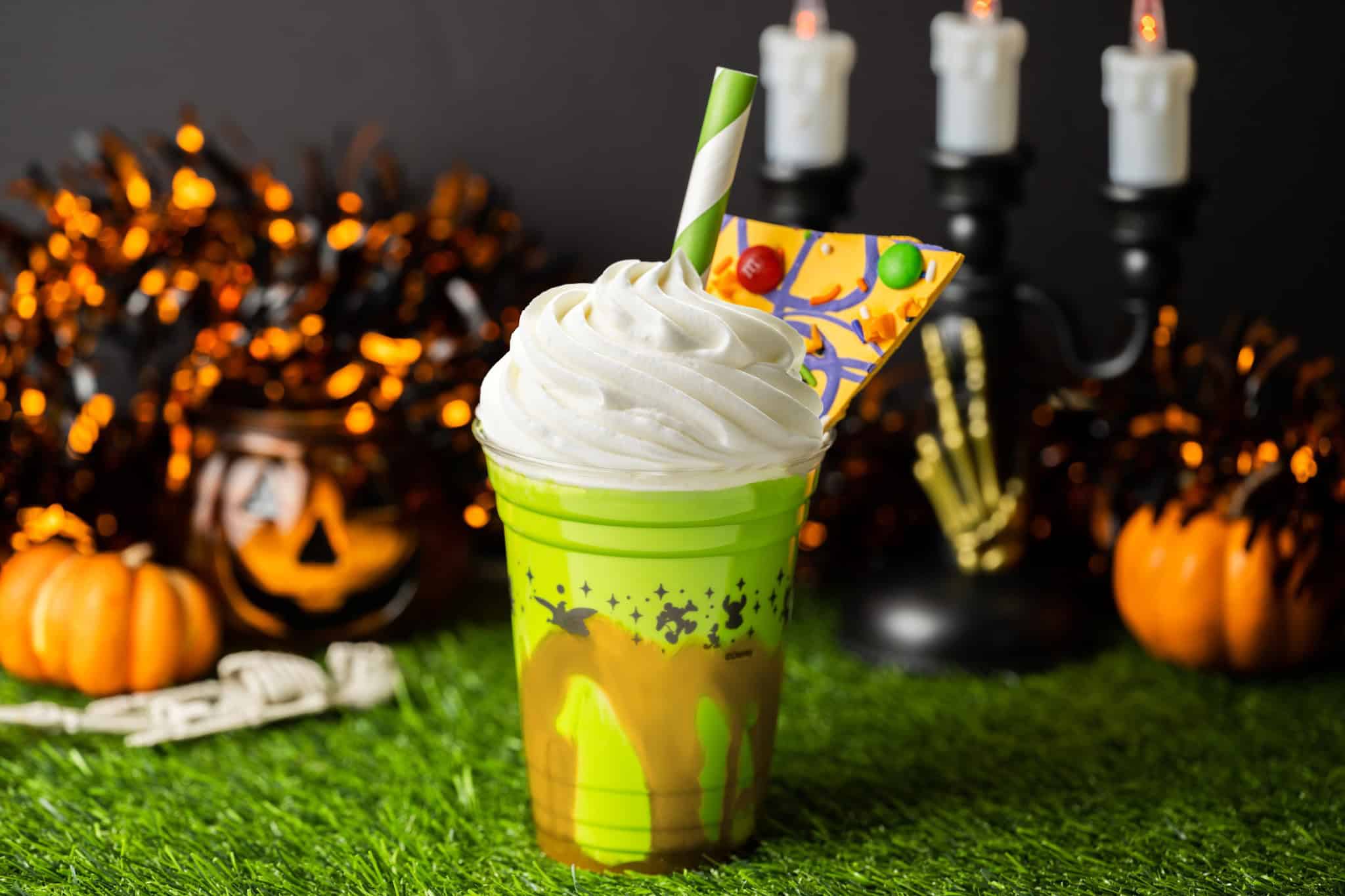 a shake with loads of whip cream and a green and white swirl straw 