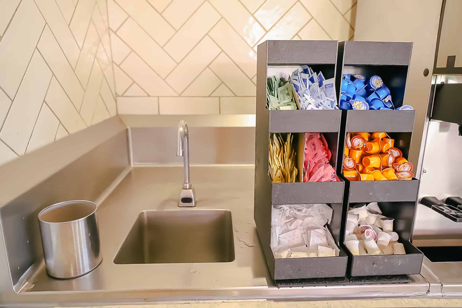 mug wash sink with creamers and assorted sweeteners sitting next to it
