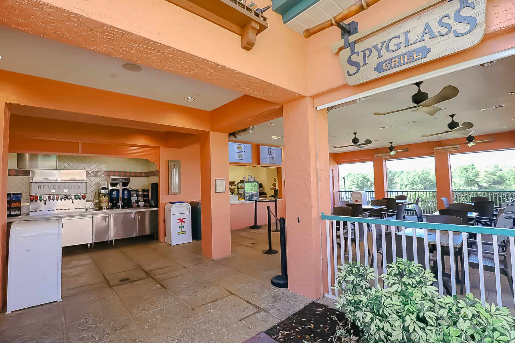 Shows the Spyglass Grill sign, dining area, beverage refill station, and counter to place orders. 