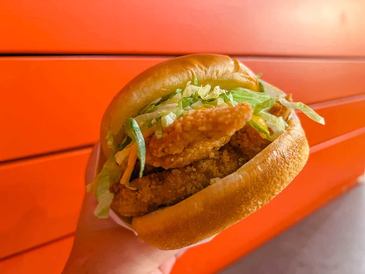 A person holding a chicken finger sandwich to show how large it is in size. 