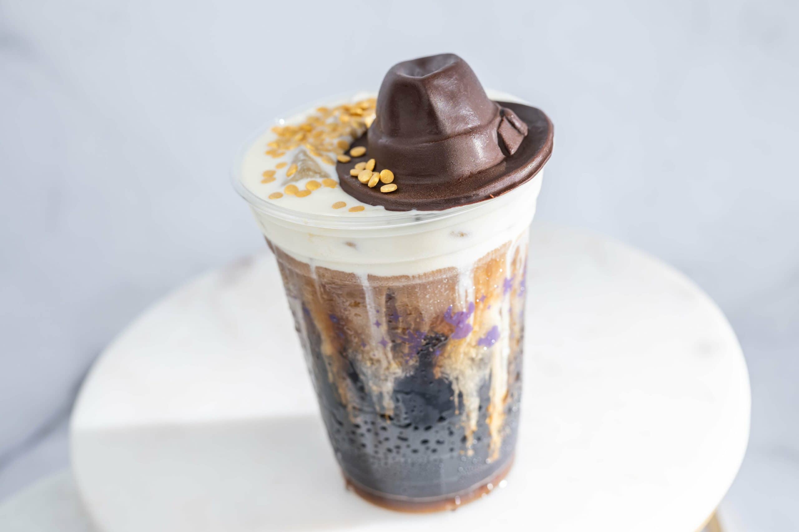 a cup of cold brew coffee with a brown fedora chocolate piece made to look like Indiana Jones hat