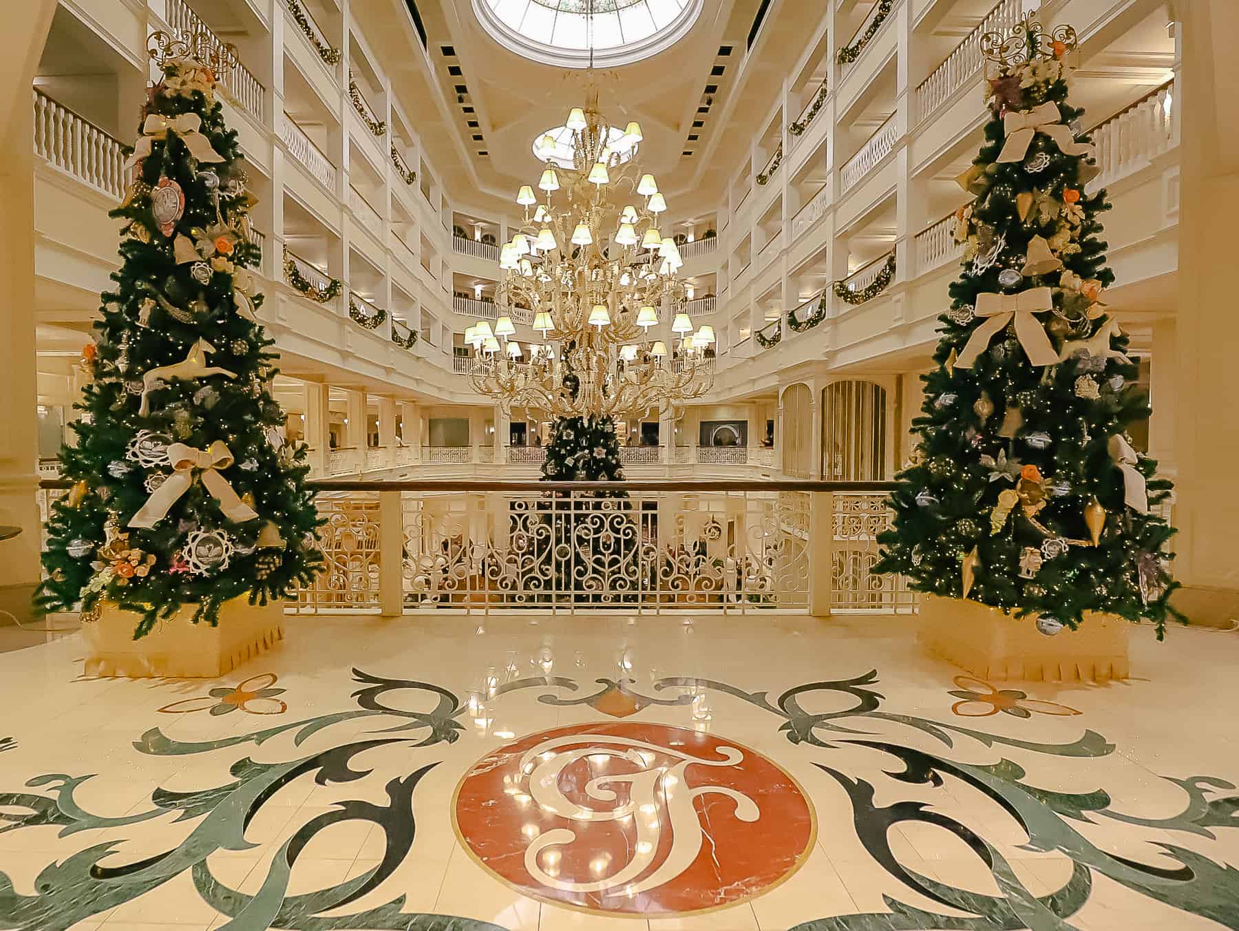 Two trees sit on each side of the Grand Floridian's logo in the marble tile flooring. 