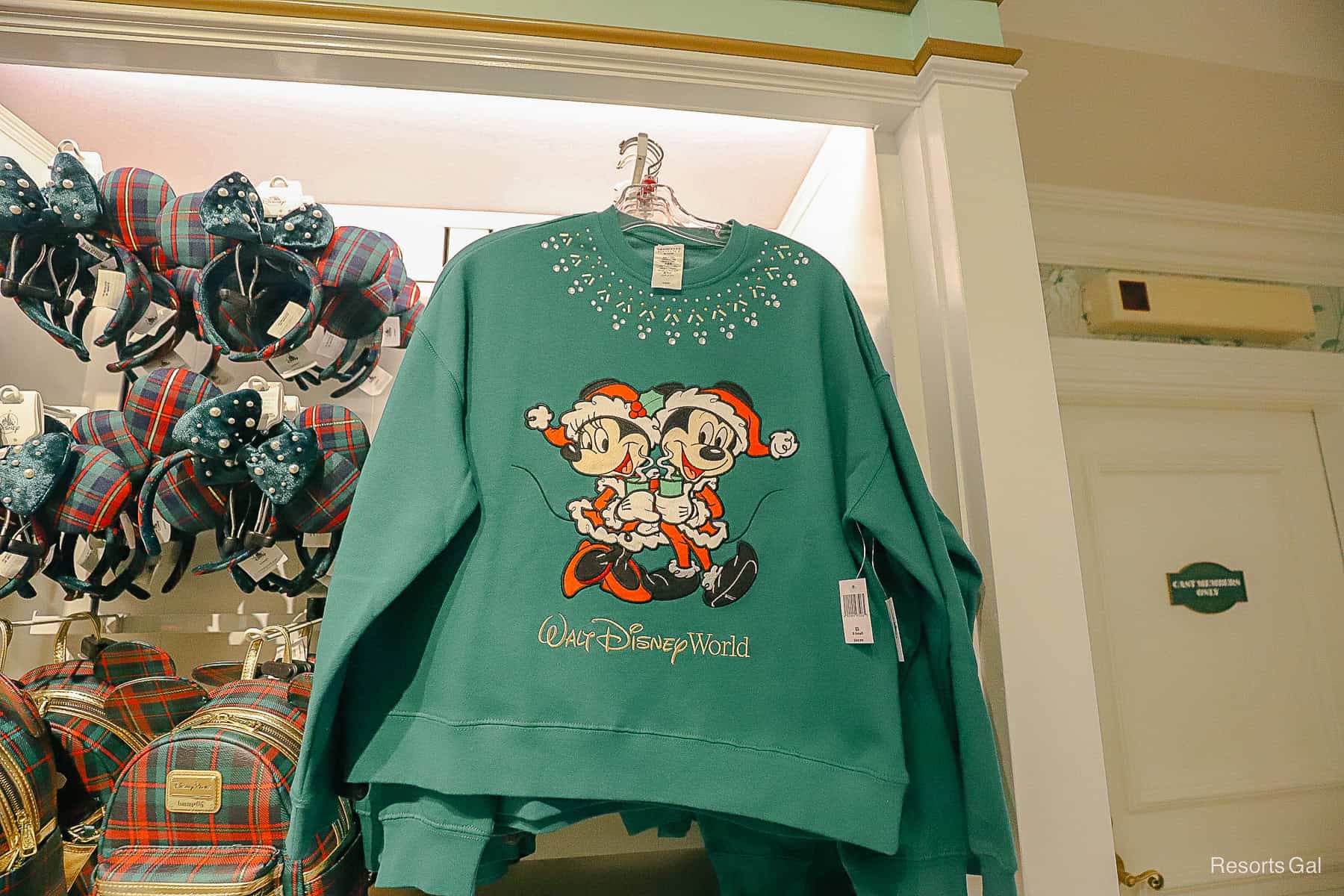 green sweatshirt with Mickey and Minnie dressed as Santa Claus and Mrs. Clause holding hot drinks