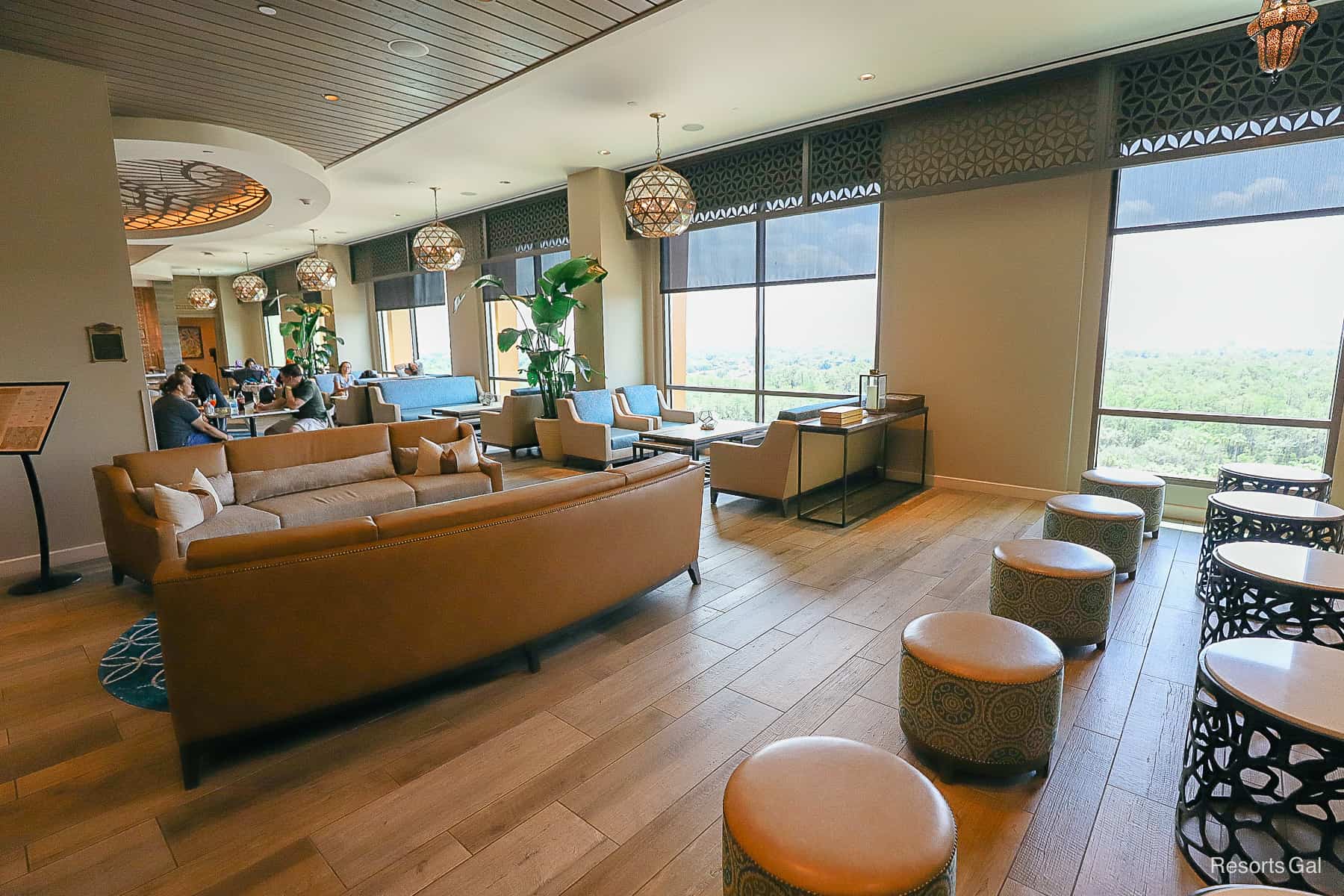 various seating areas in the lounge with light wooden floors and a wall of windows in the backdrop 