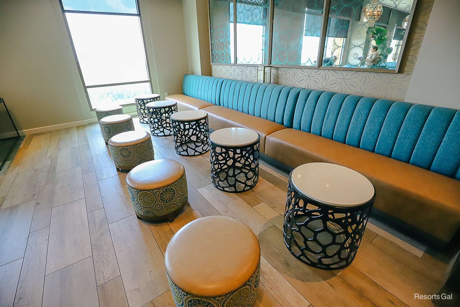 a row of small stools with cocktail tables and a banquette style bench covering the entire back wall 