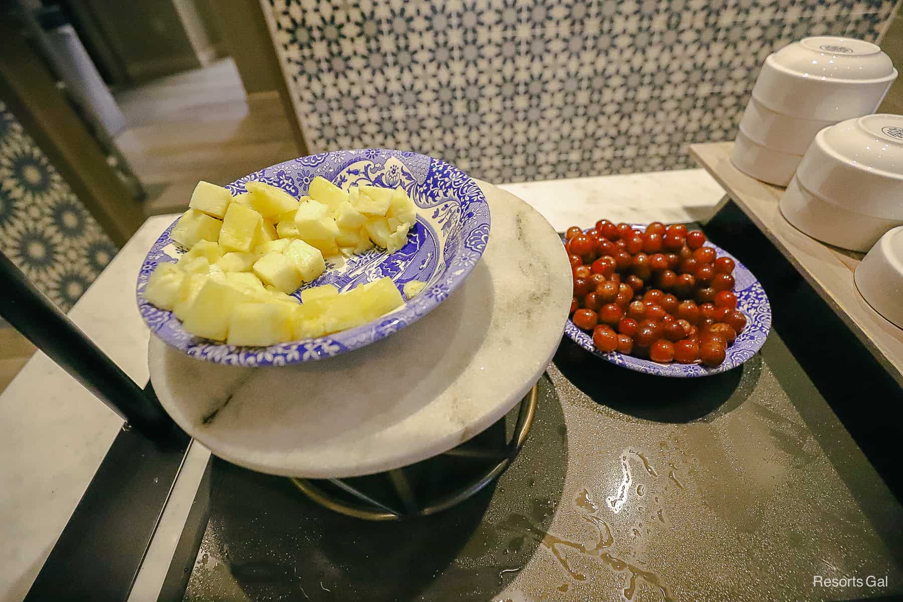 a bowls of pineapple and a side of grapes 