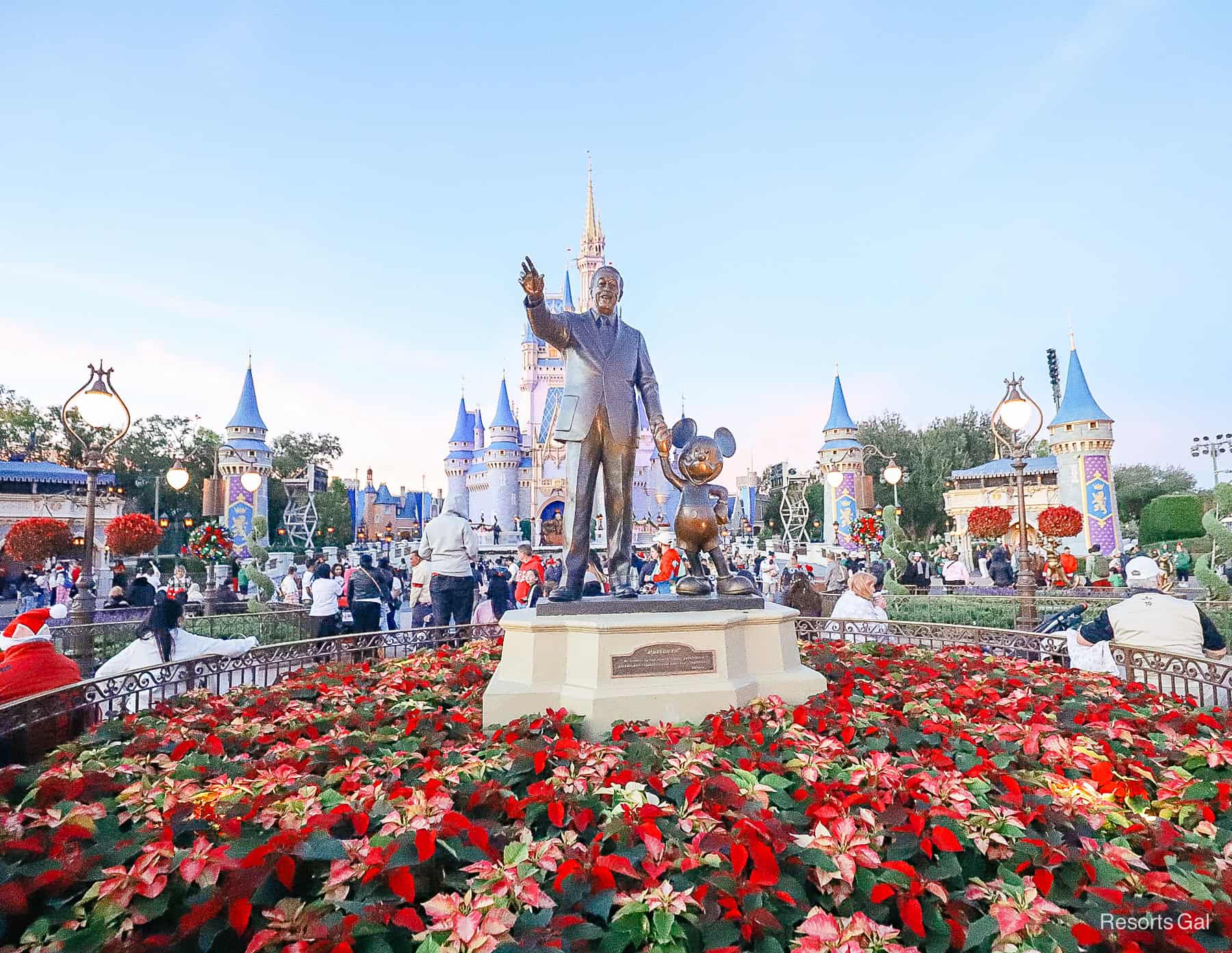 the partners statue in front of Cinderella Castle surrounded in poinsettias