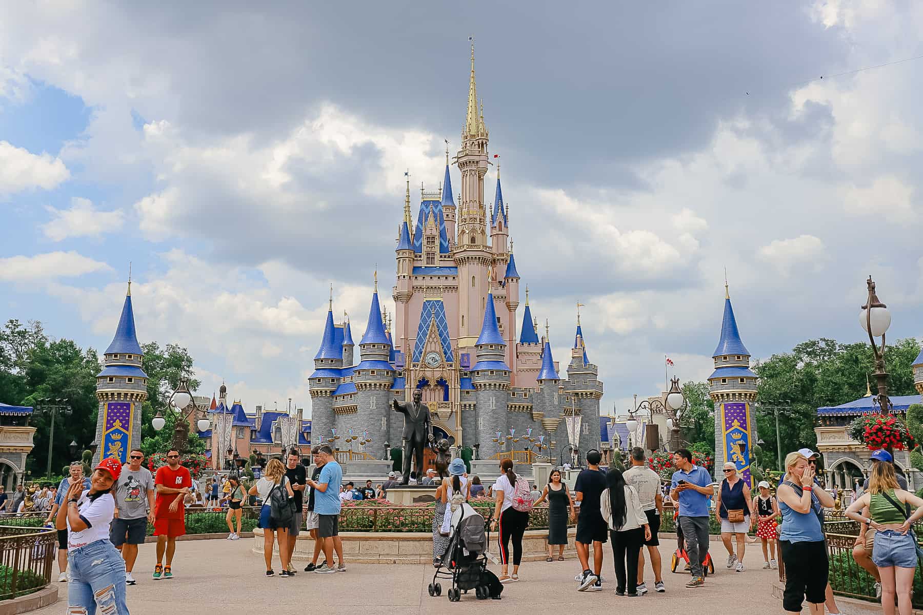 Guests posing for photos in various places in front of Cinderella Castle. 