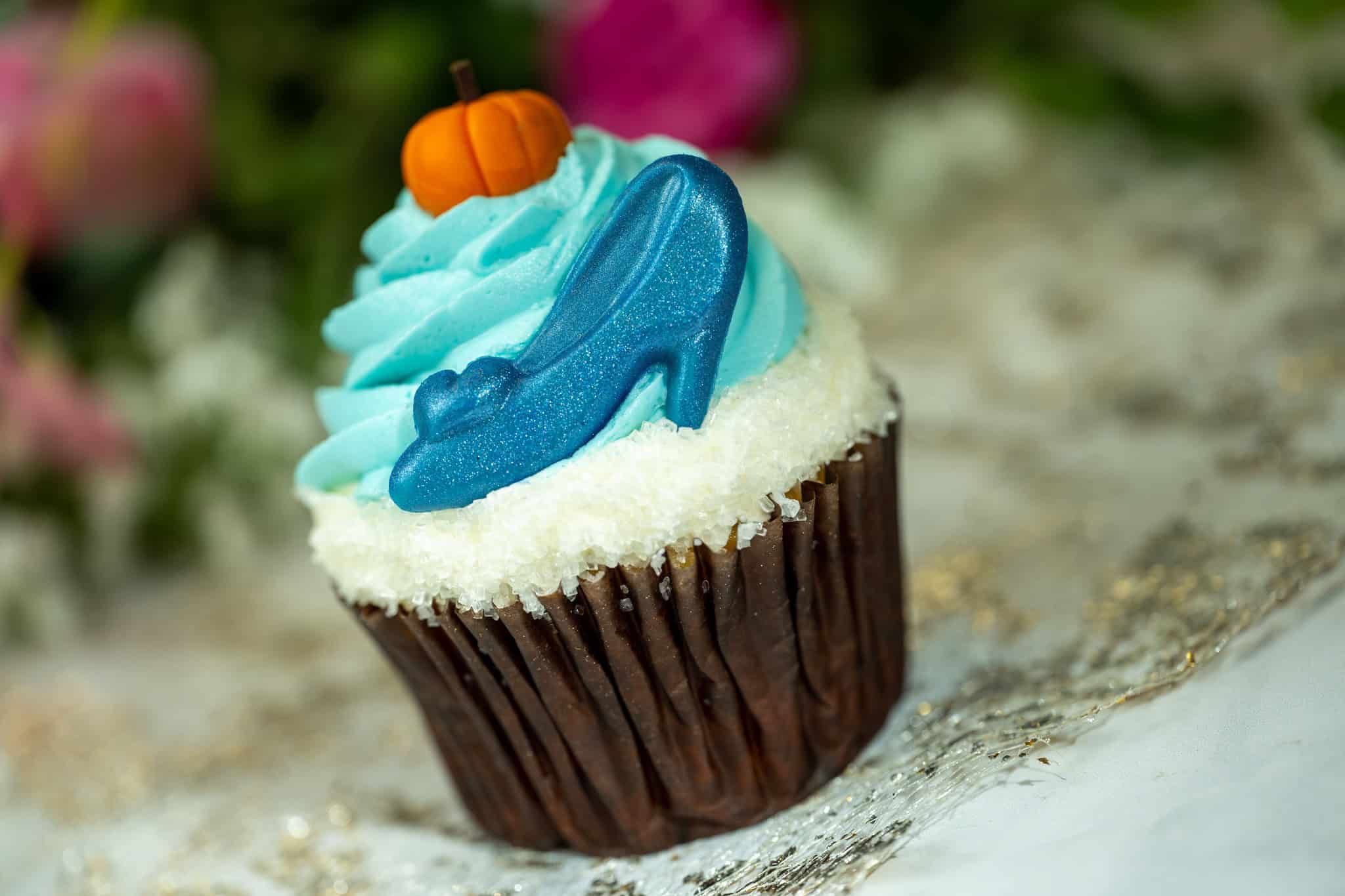 a cupcake with a shiny blue shoe and orange candy pumpkin 