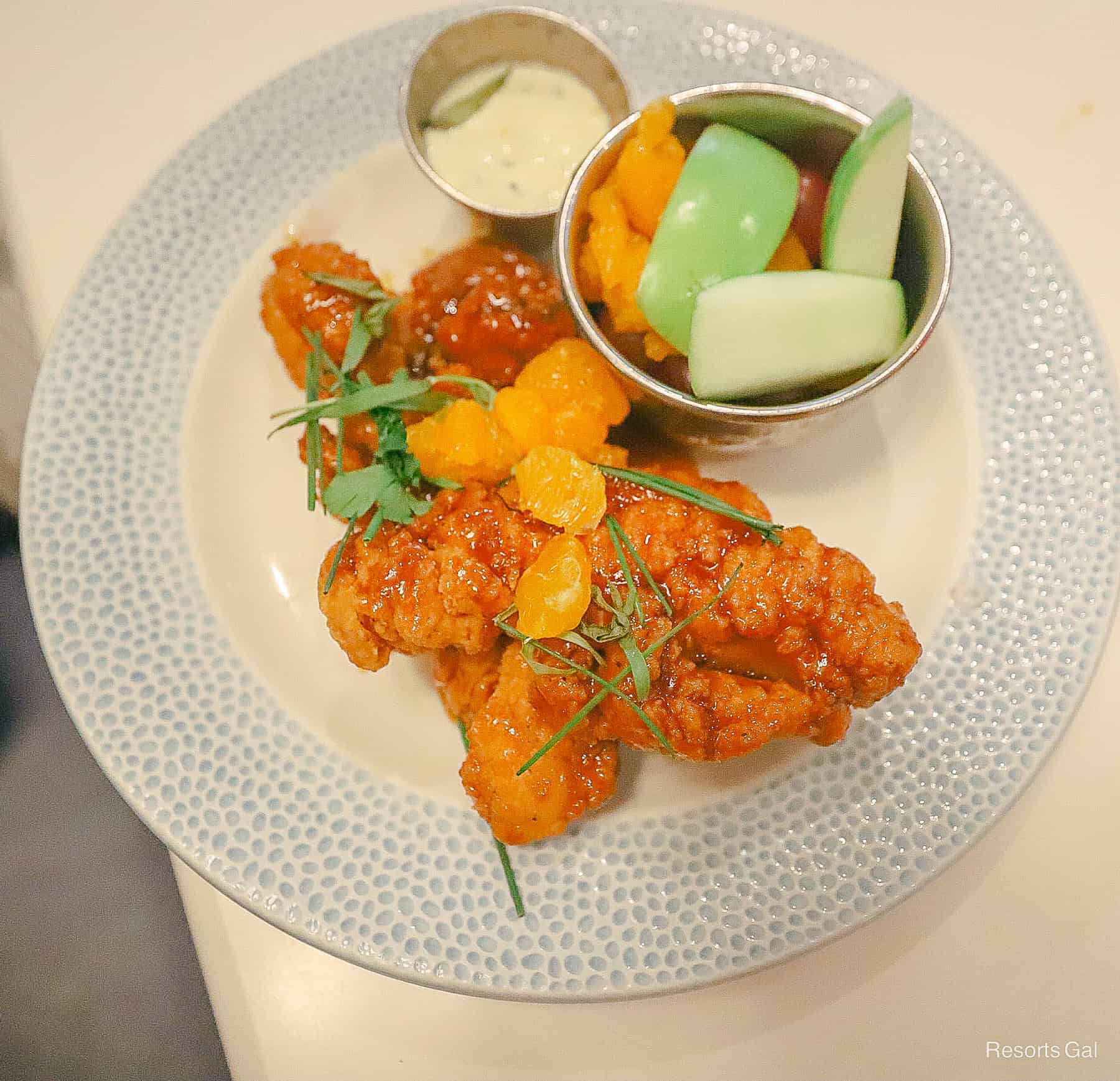an order of sauced chicken strips with a side of fruit