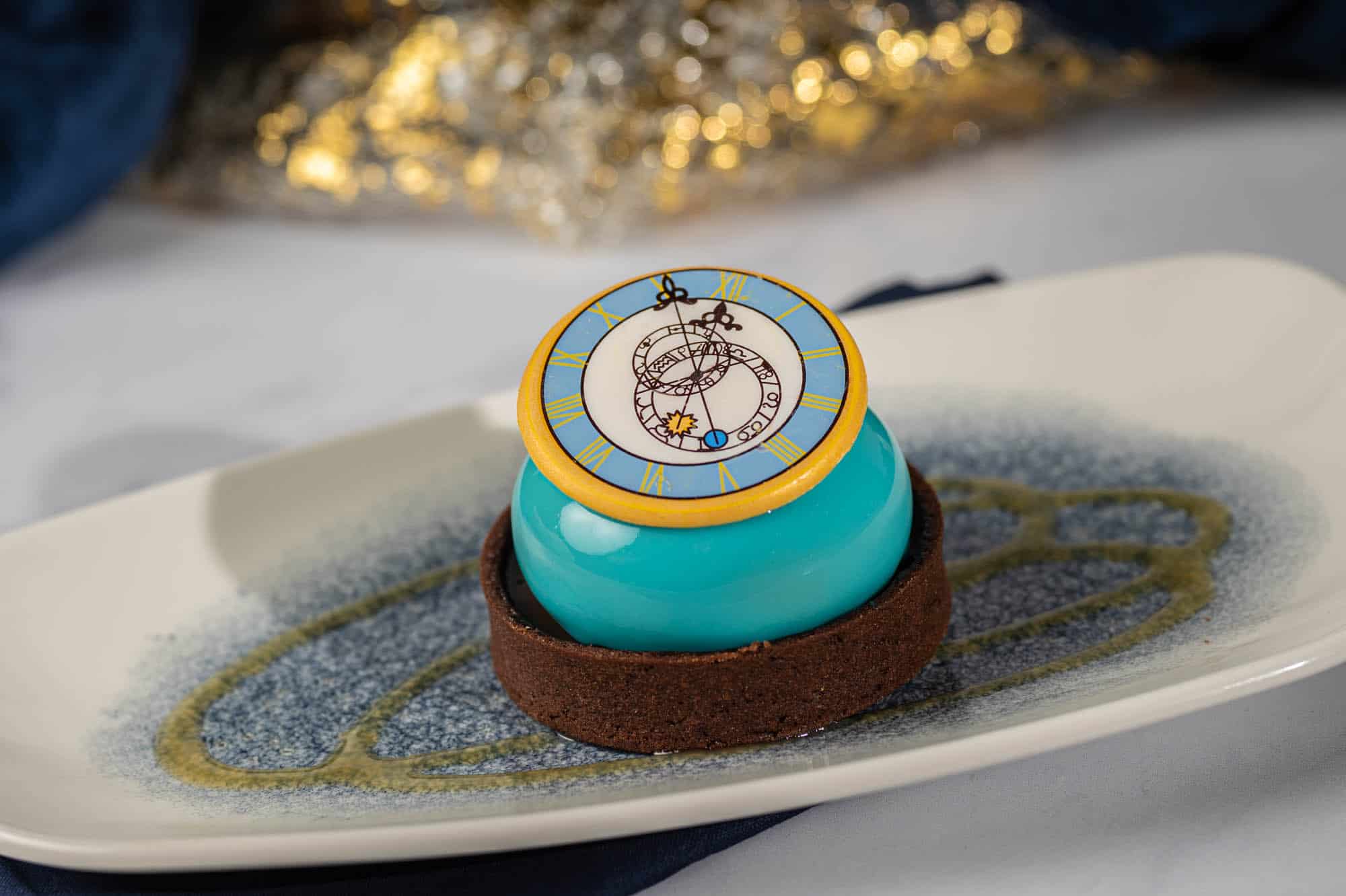 a dessert that's chocolate and blue in the center with a clock white chocolate piece on top 