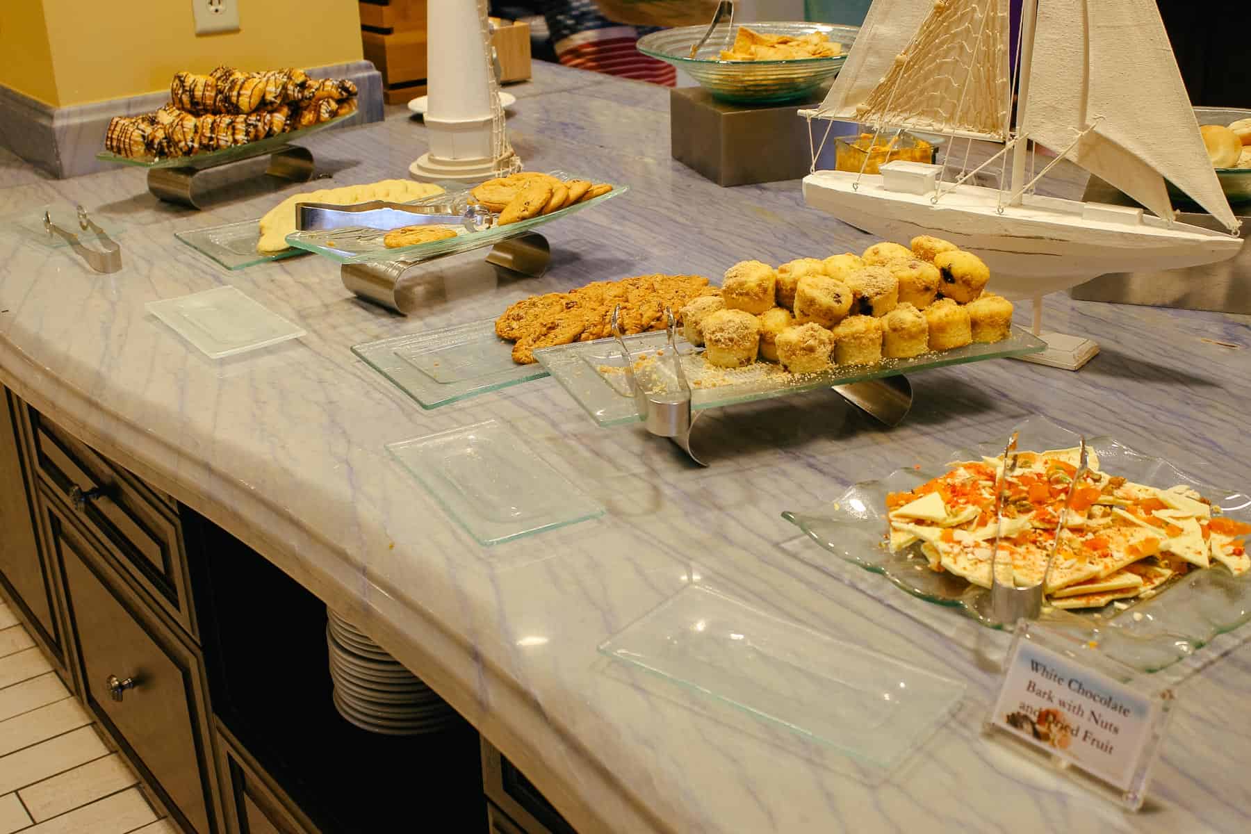 a tray of muffins, white chocolate bark with fruits, and other desserts 