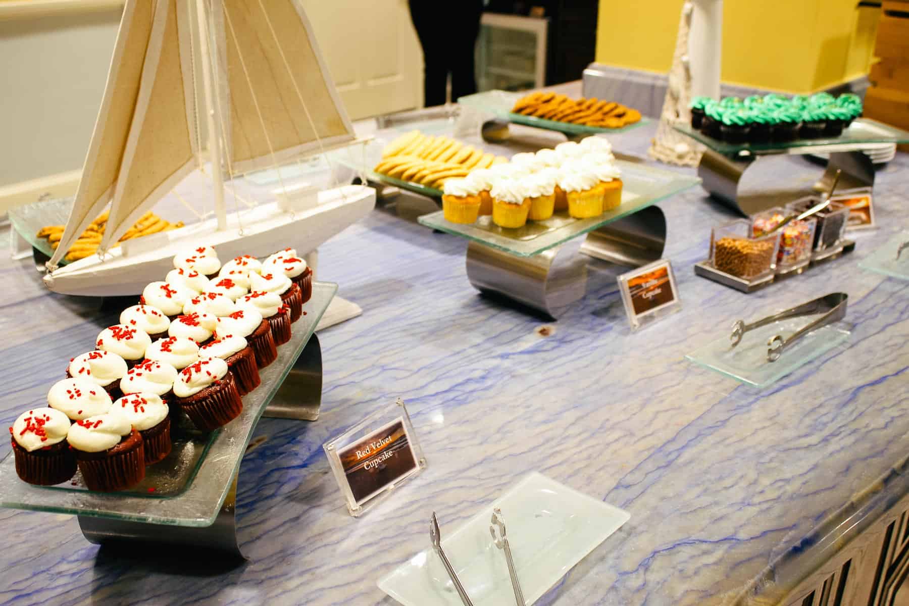 a platter with red velvet cupcakes and other cupcakes and cookies in the background 