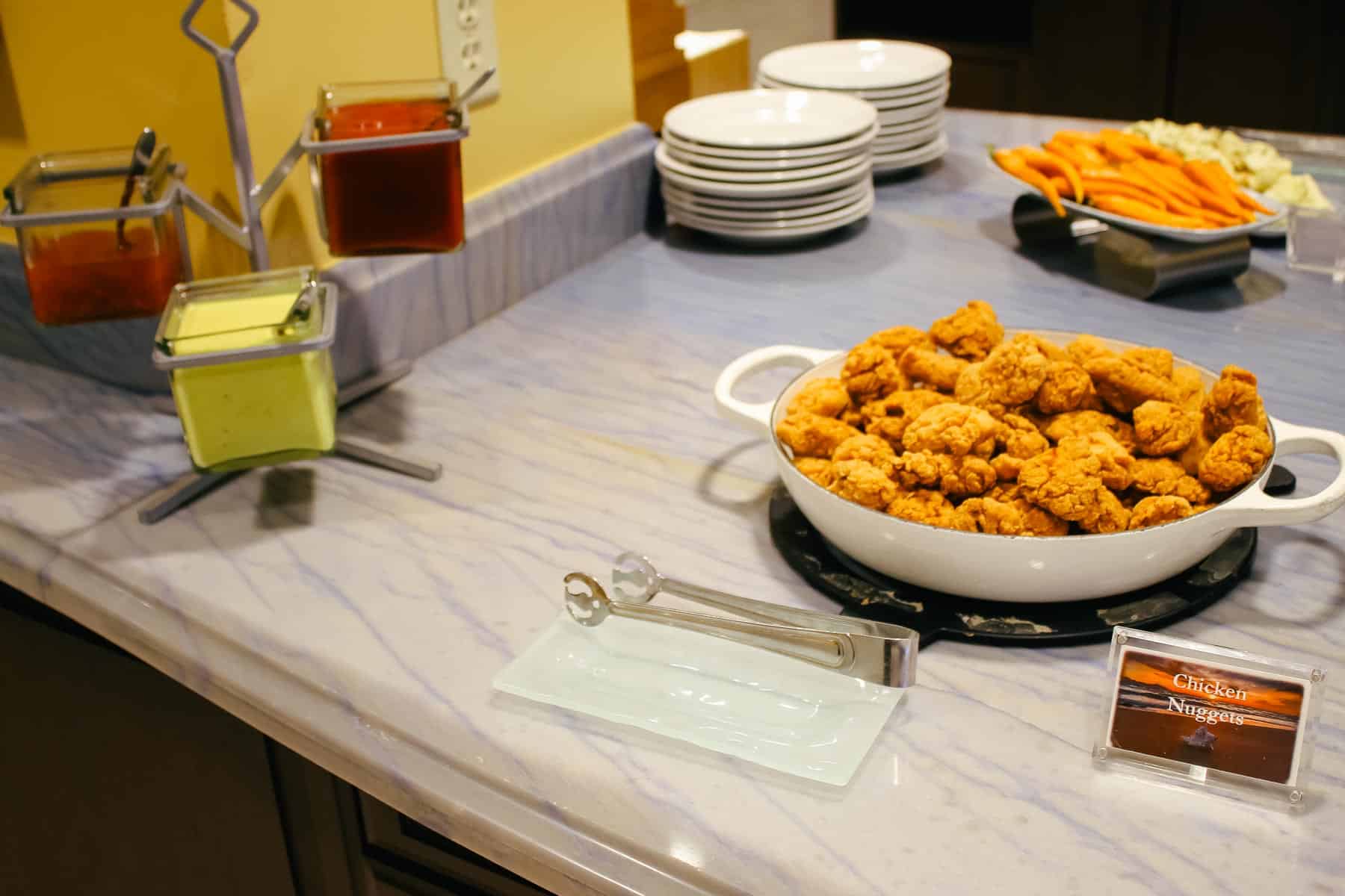 a platter with chicken nuggets and various dipping sauces on the left side 