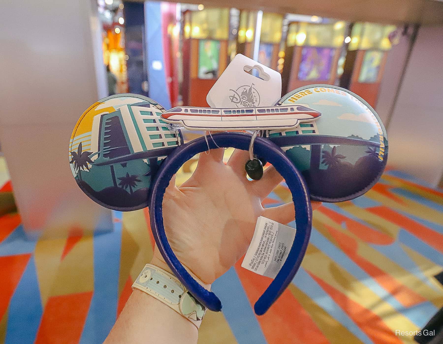 a pair of monorail themed Minnie Ears with "Here Comes the Monorail" written on one ear